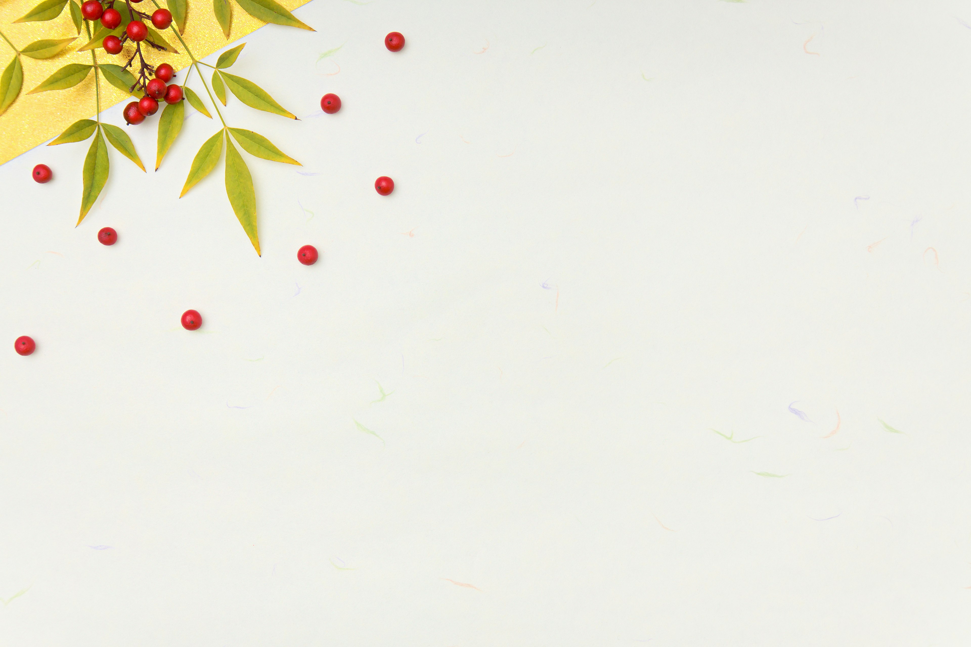 Design featuring red berries and green leaves scattered on a white background