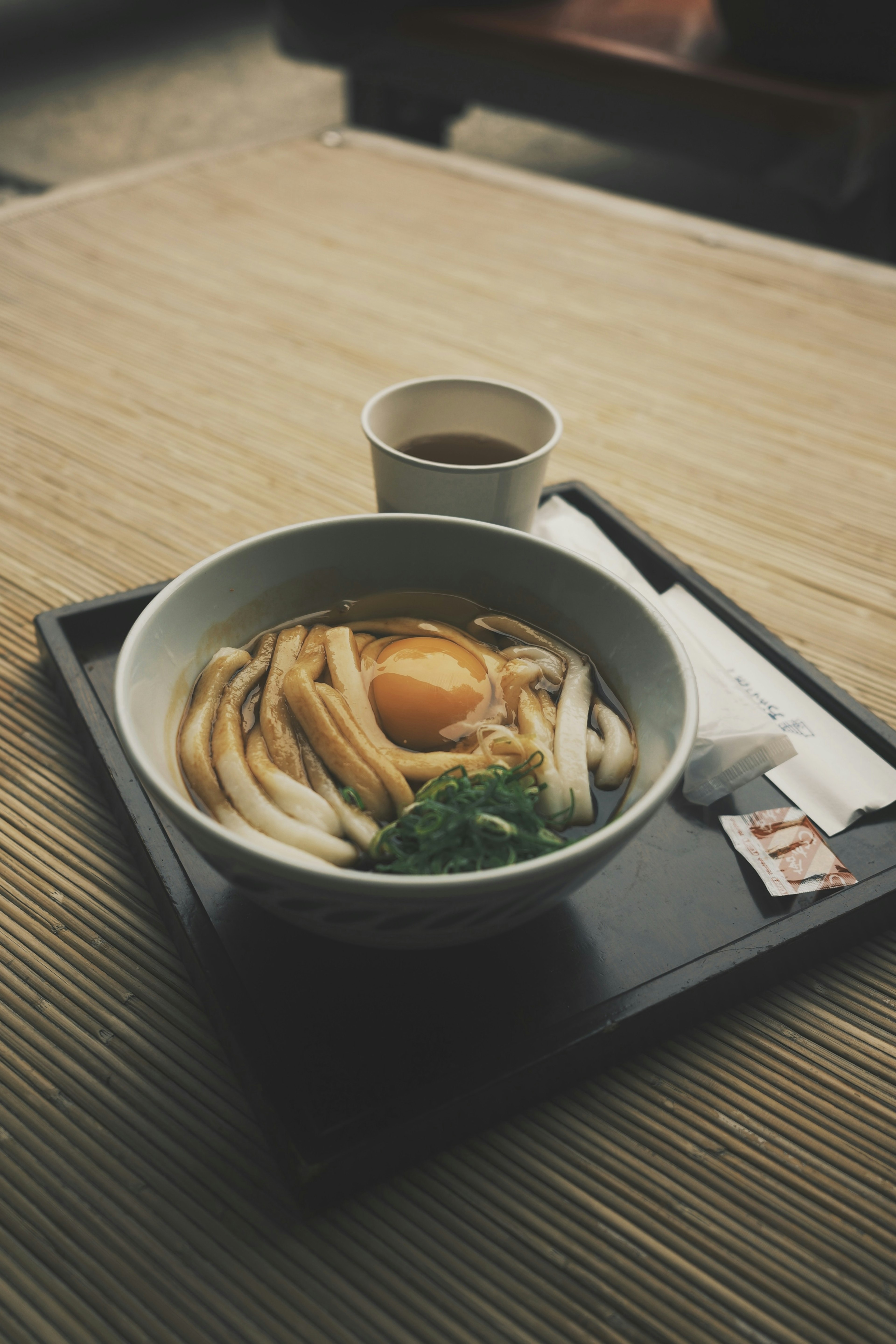 Mangkok mie udon hangat dengan telur mentah di atasnya