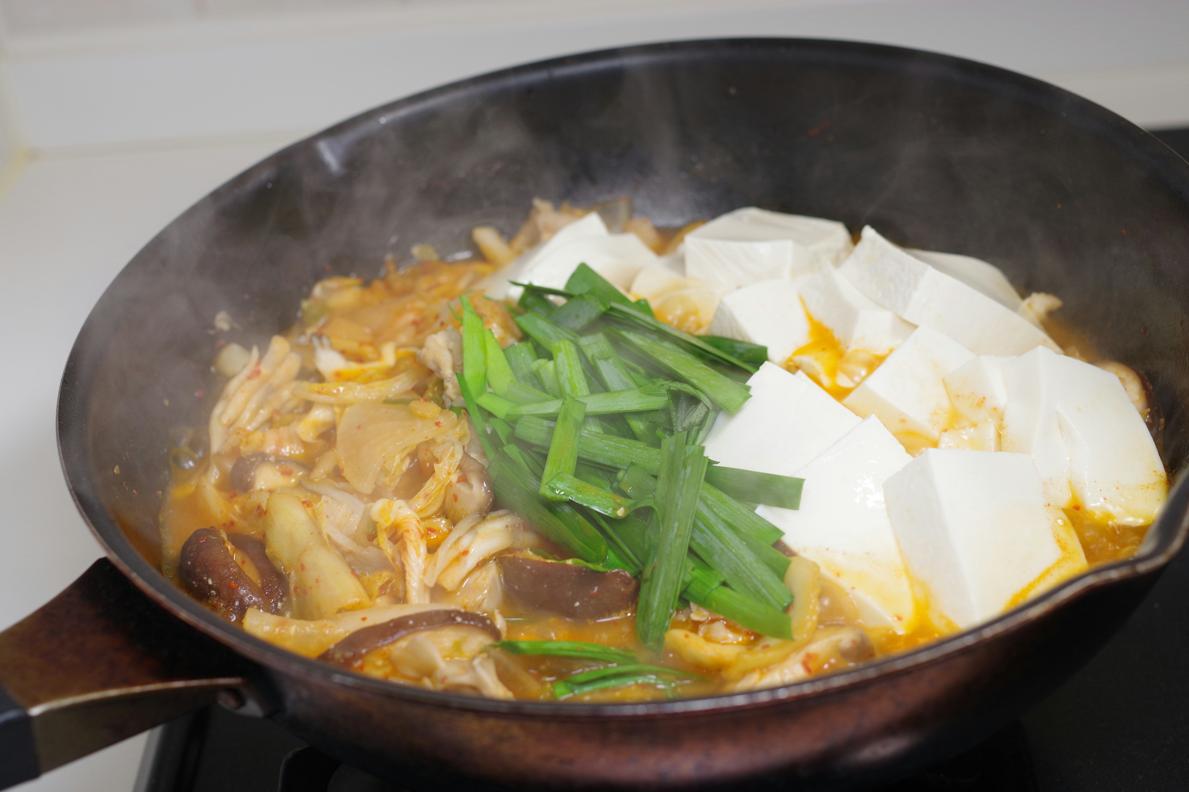 Hidangan tahu dan sayuran yang sedang dimasak di dalam panci