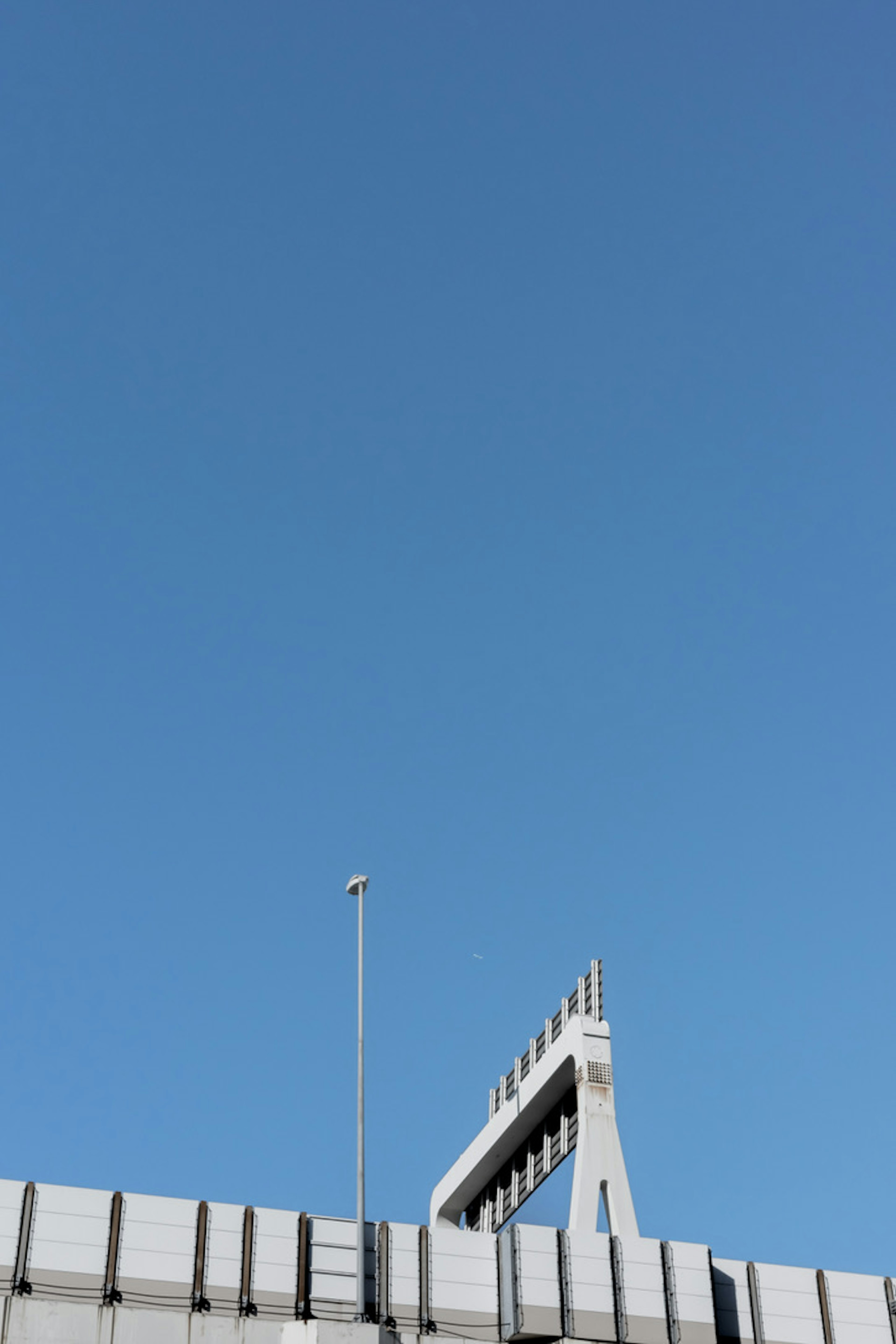 Partie d'un bâtiment moderne avec une structure élevée sous un ciel bleu clair