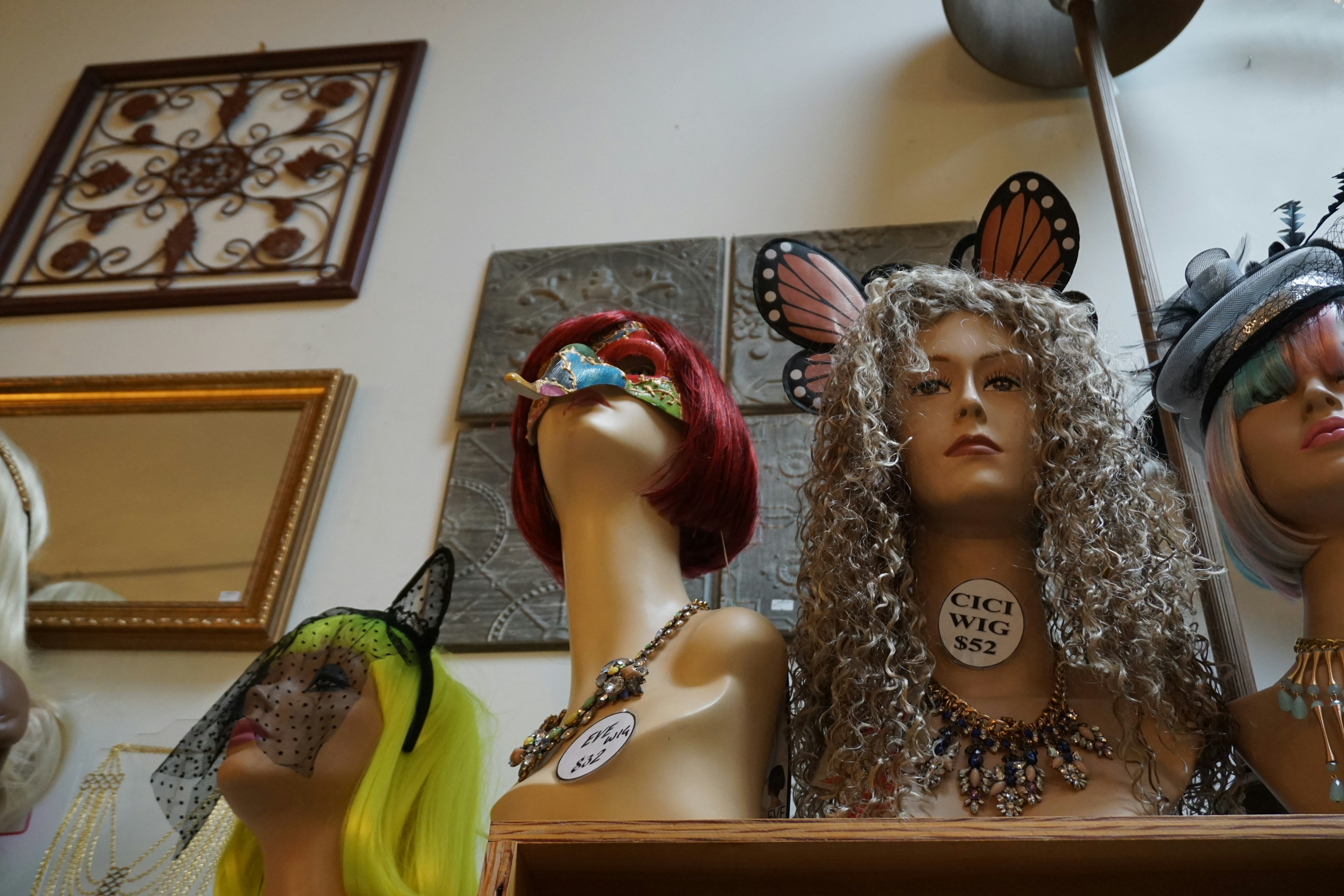 Mannequins colorés avec des perruques exposés dans un intérieur de magasin