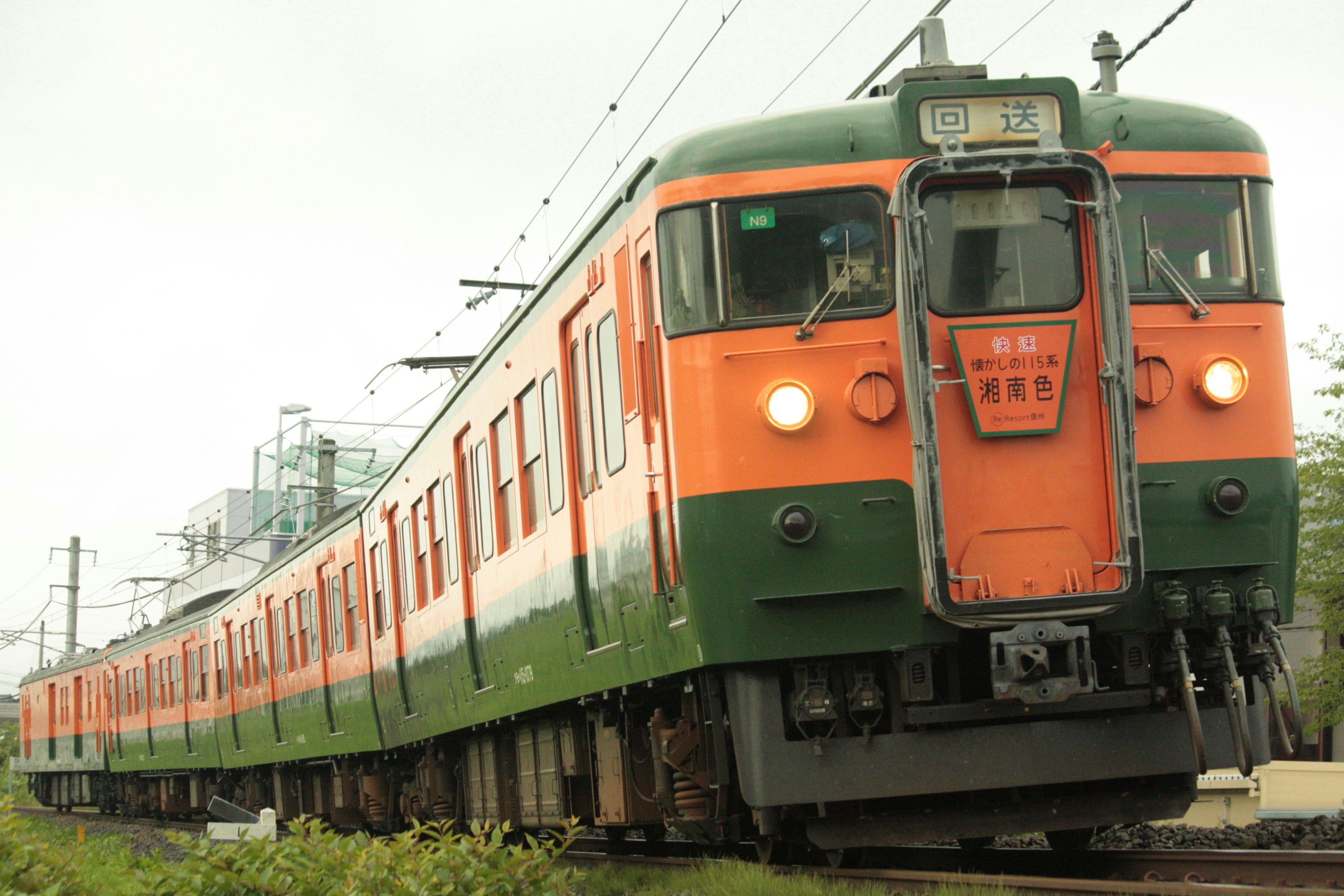 An orange and green train running on tracks