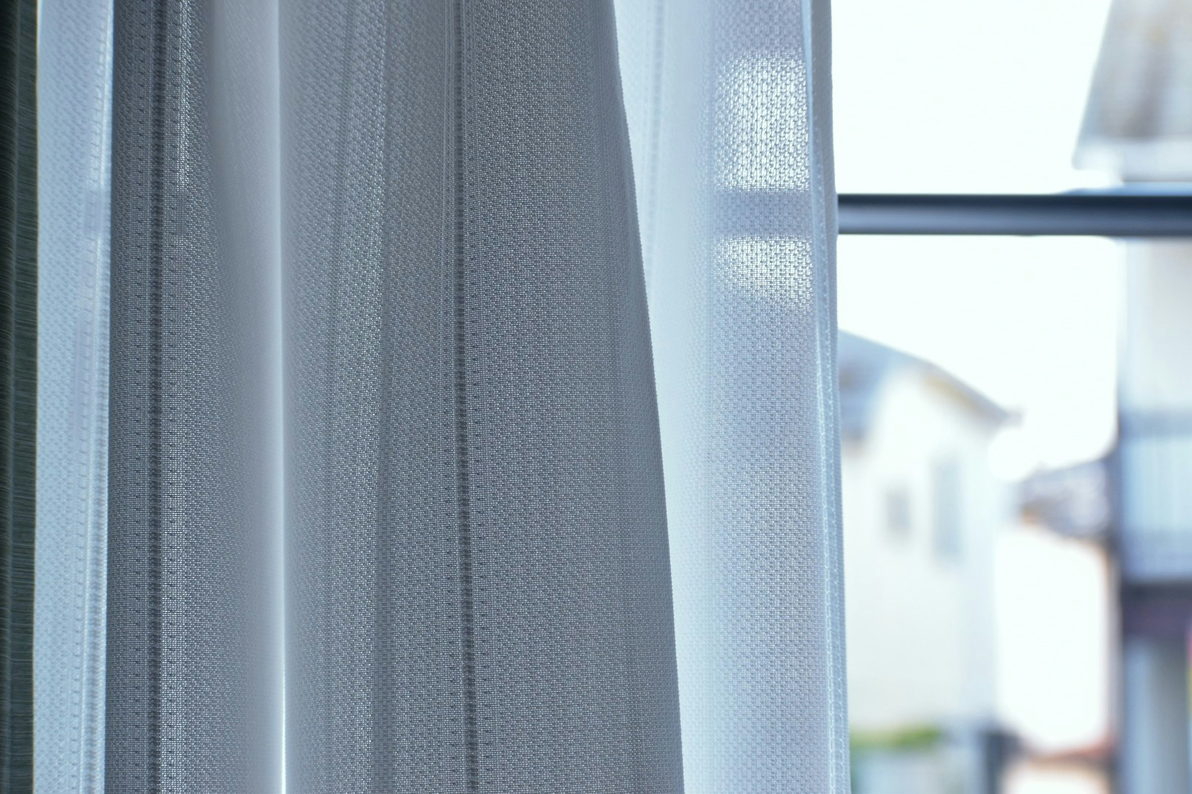 Sheer white curtains gently swaying by the window