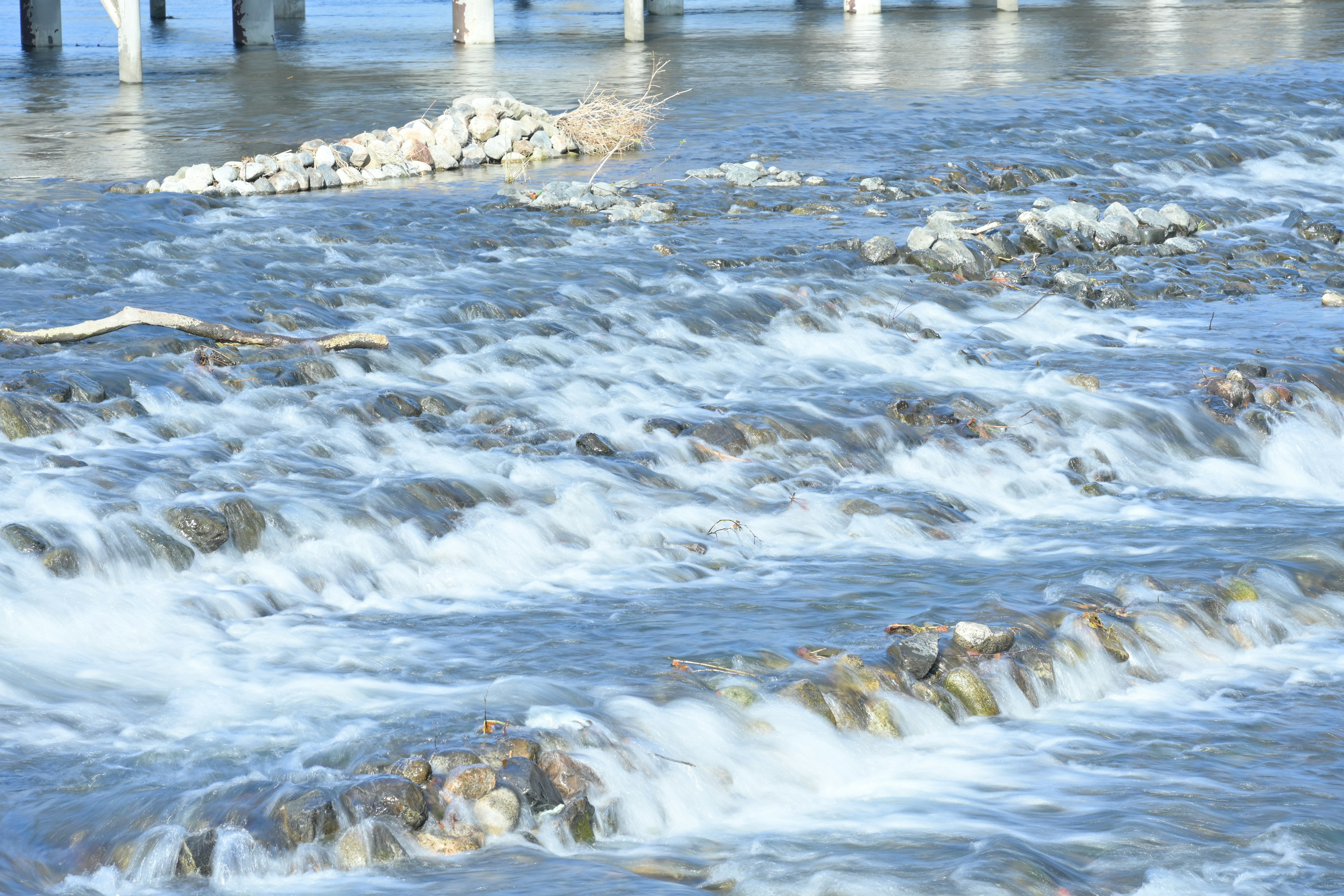 水が流れる川の風景と橋の柱が見える