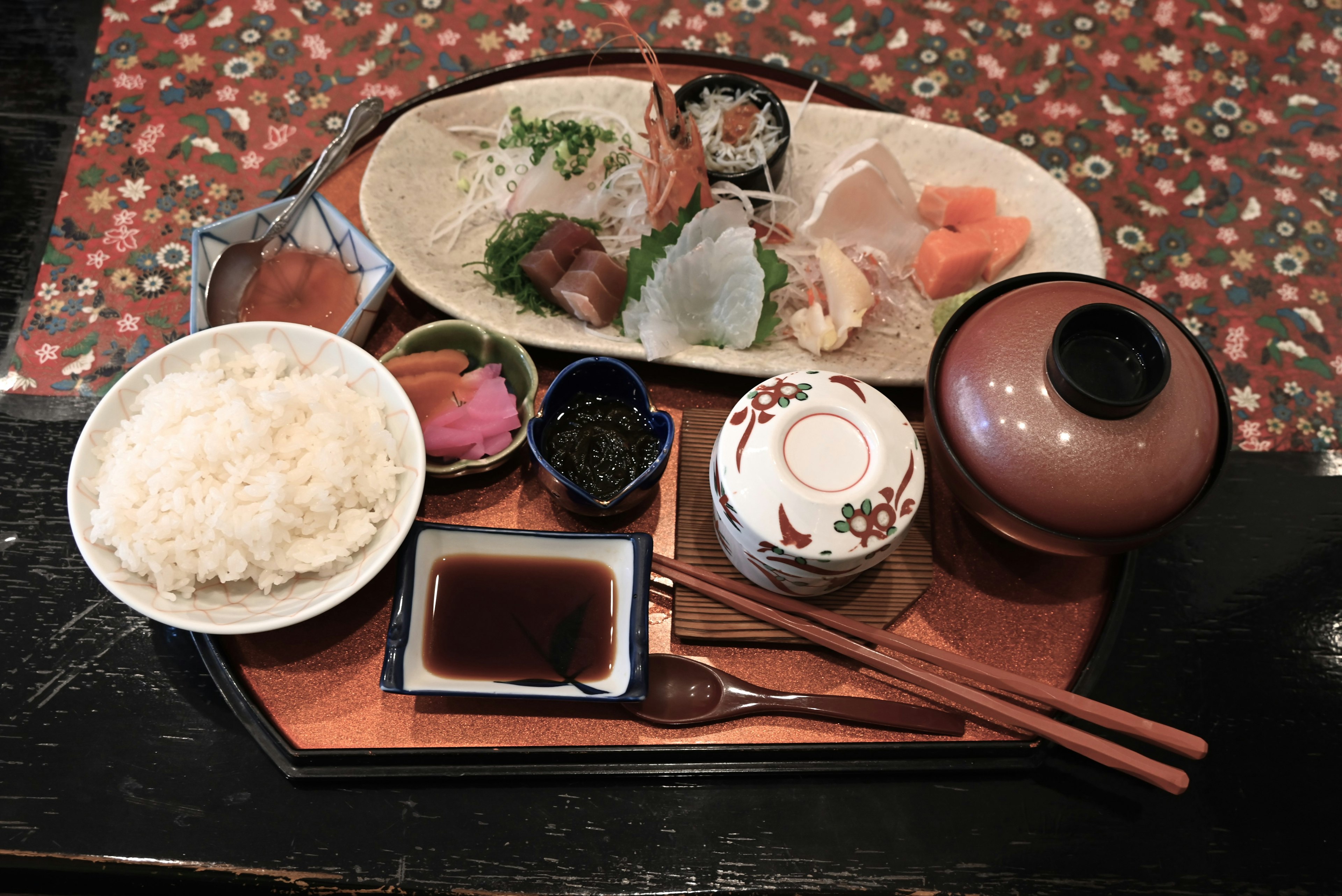 Hidangan Jepang yang disajikan dengan indah, termasuk sashimi dan nasi di atas nampan kayu