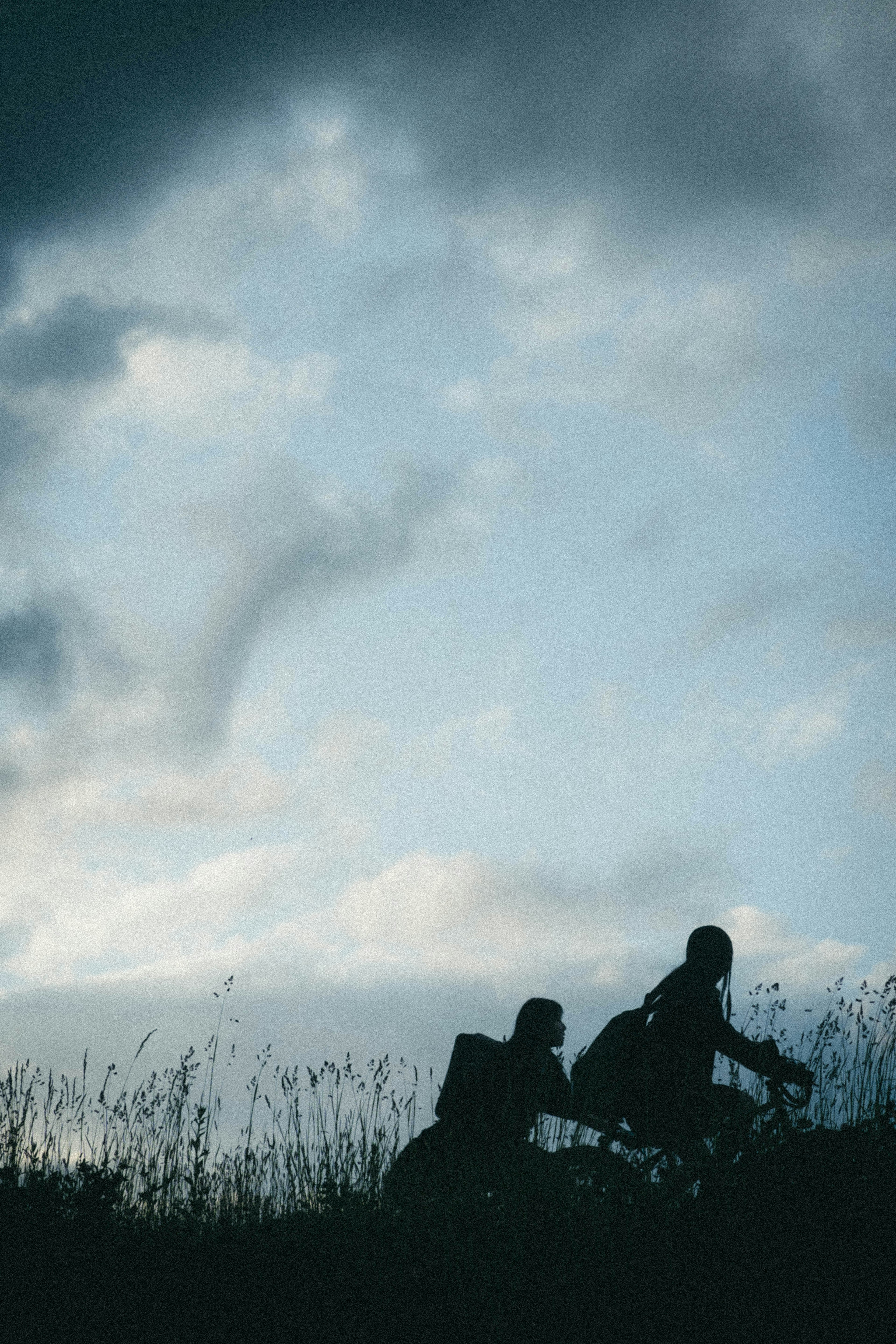 Silhouette de deux personnes à vélo contre un ciel nuageux