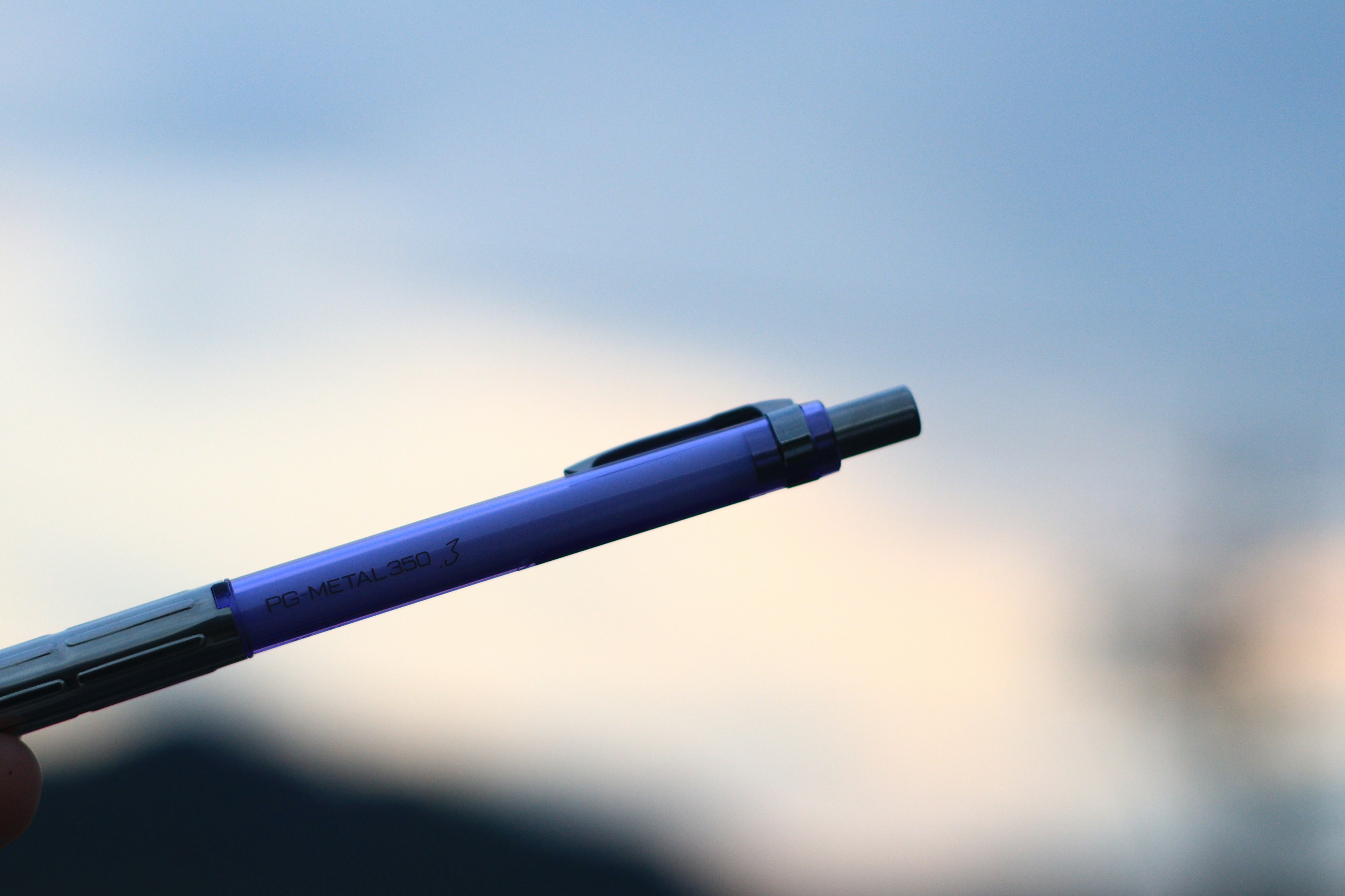 A purple pen against a blurred sky background