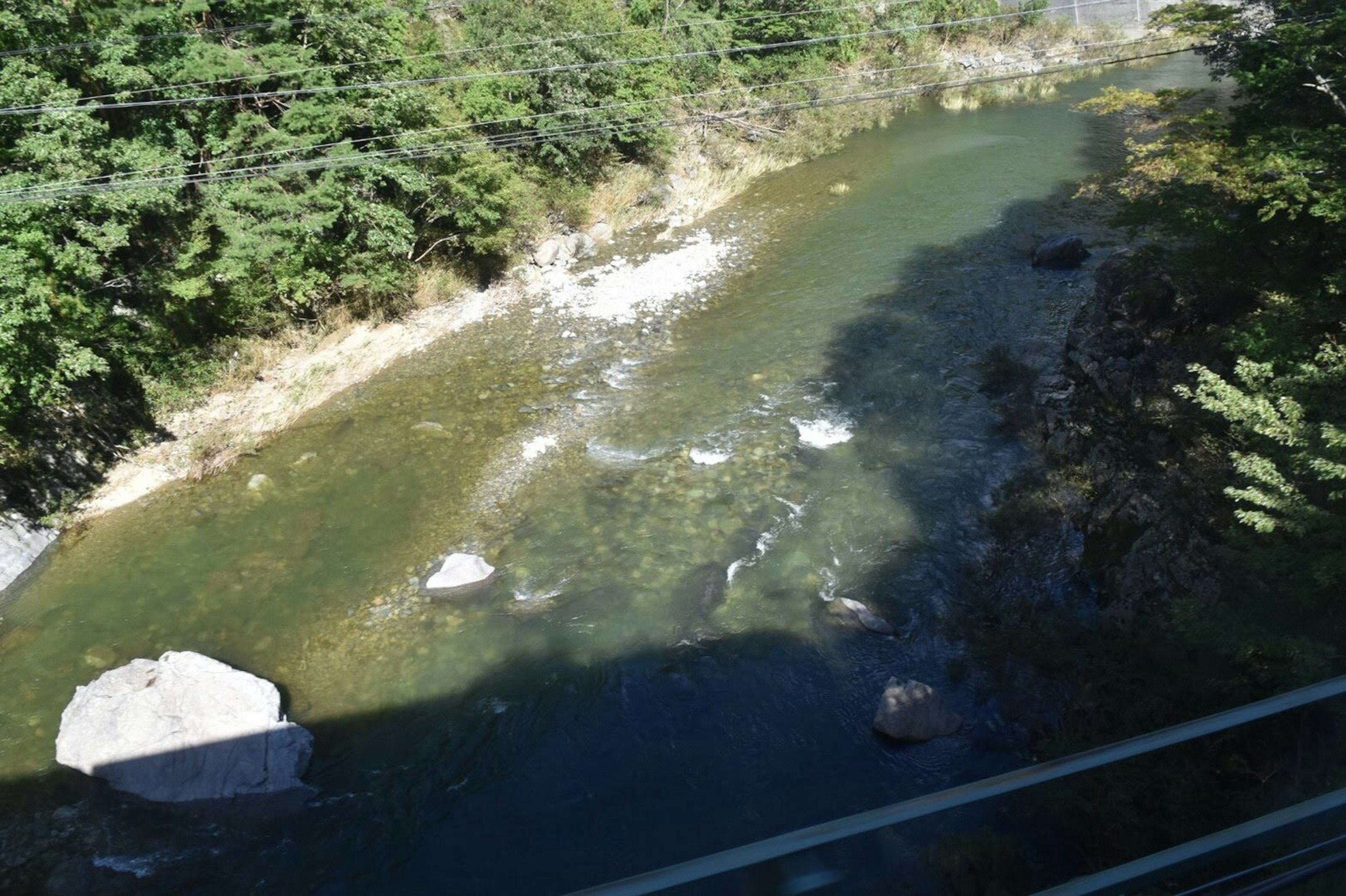 Malersicher Blick auf einen ruhigen Fluss, umgeben von üppigem Grün mit verstreuten Felsen