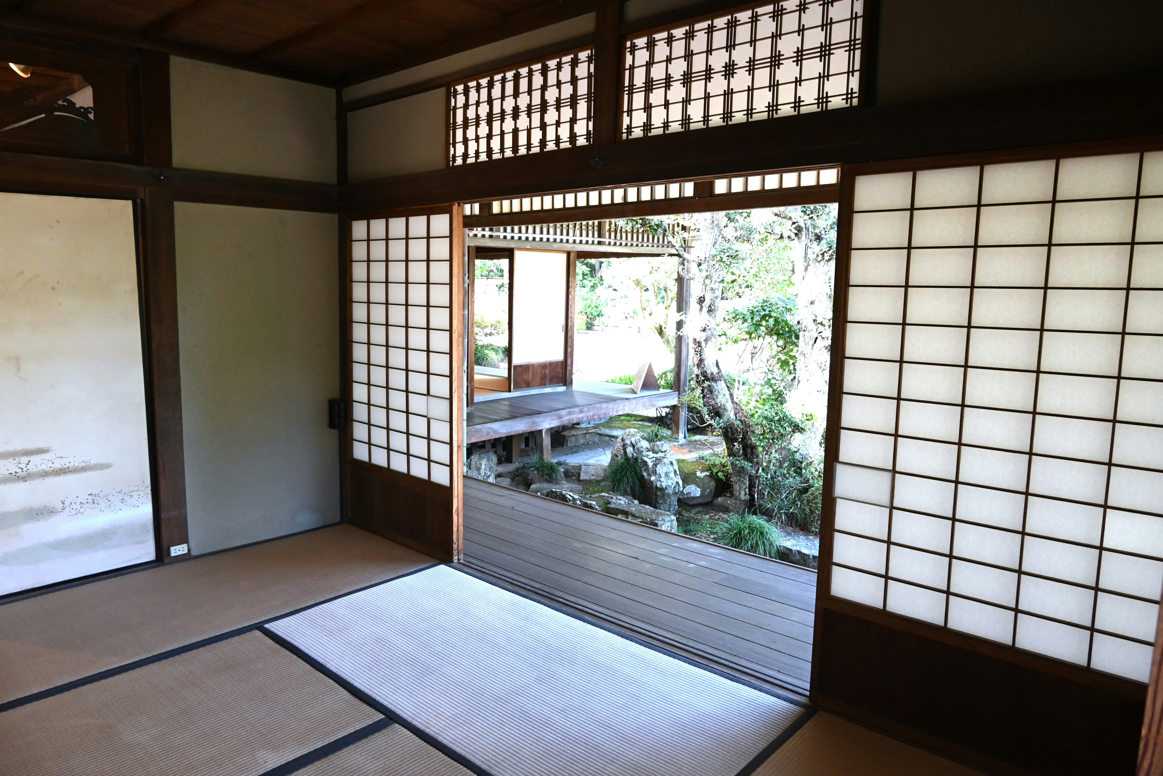 Interno giapponese tradizionale con porte shoji e tatami che si affacciano su un giardino