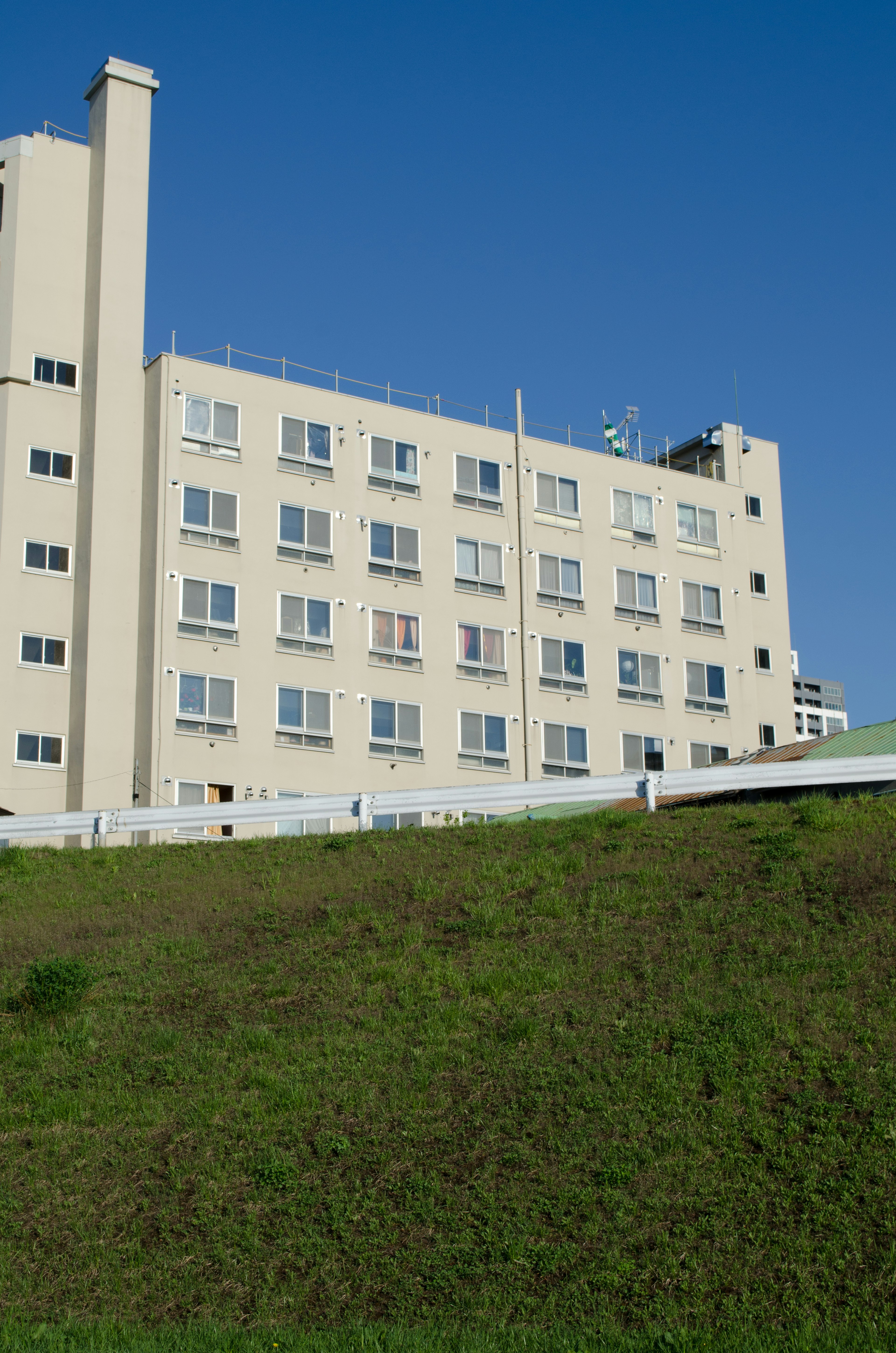 Edificio blanco bajo un cielo azul con colina verde