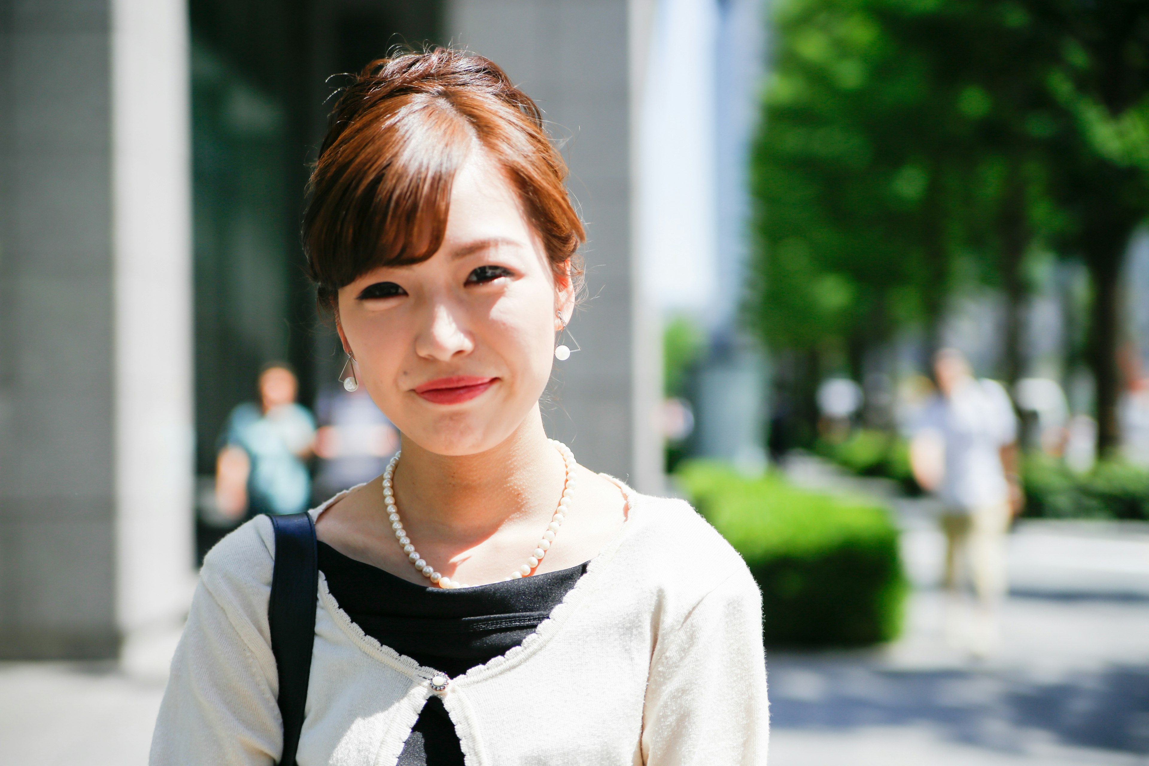 A young woman smiling in the city with green trees in the background