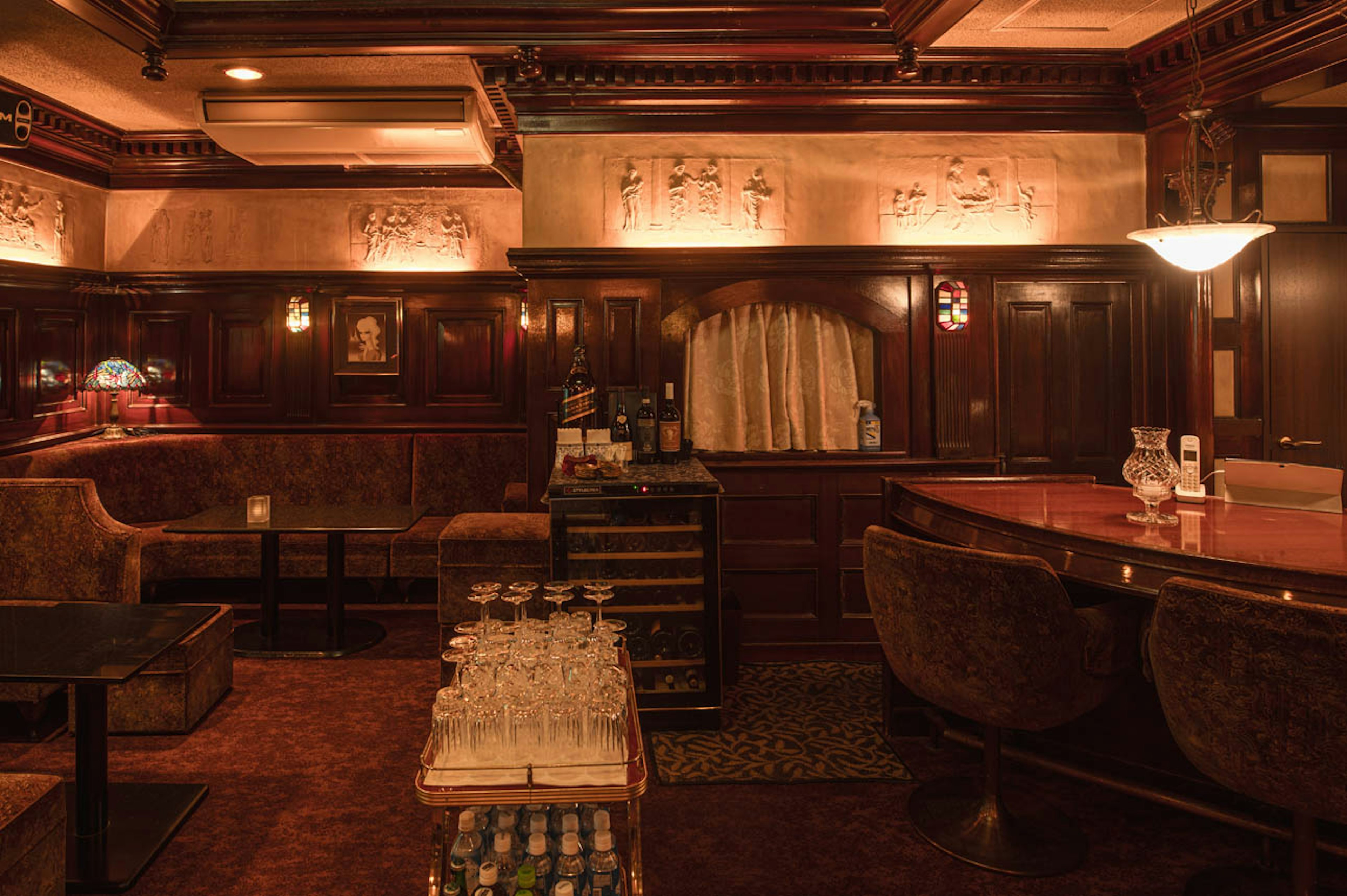 Interior de bar acogedor con decoración de madera y luz suave que incluye sofás y un mostrador