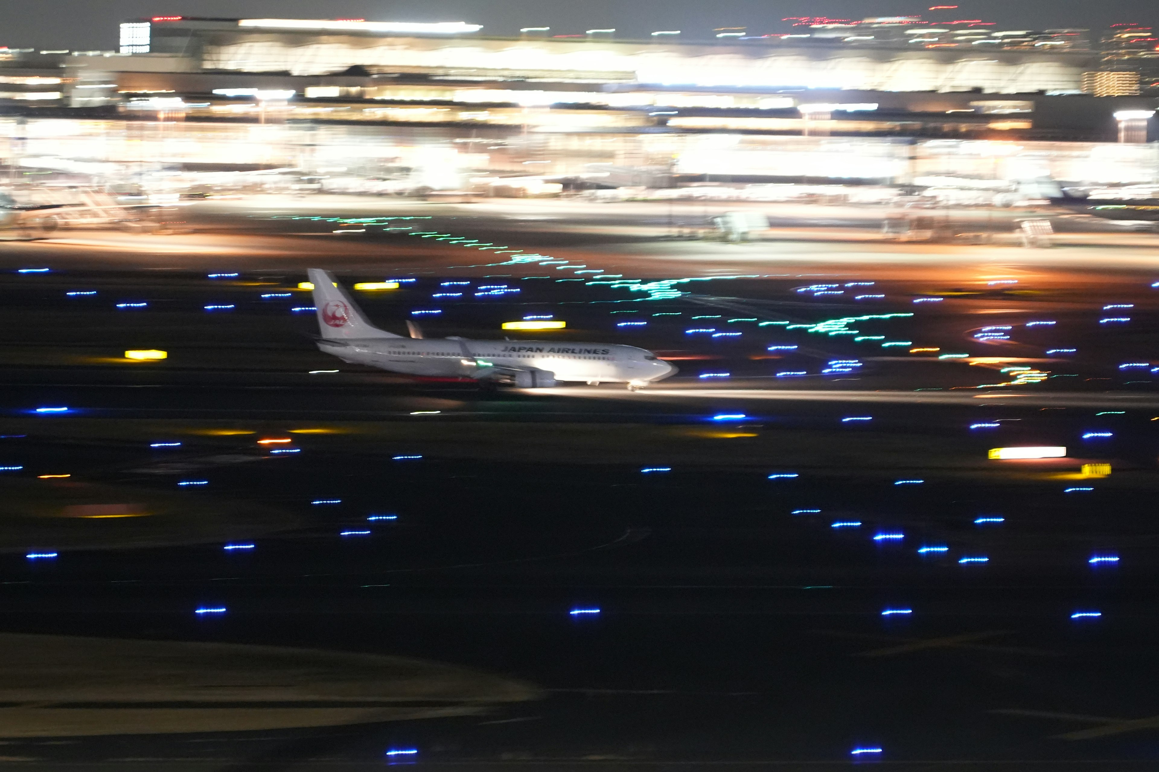 Image of an airplane landing at night with illuminated blue runway lights