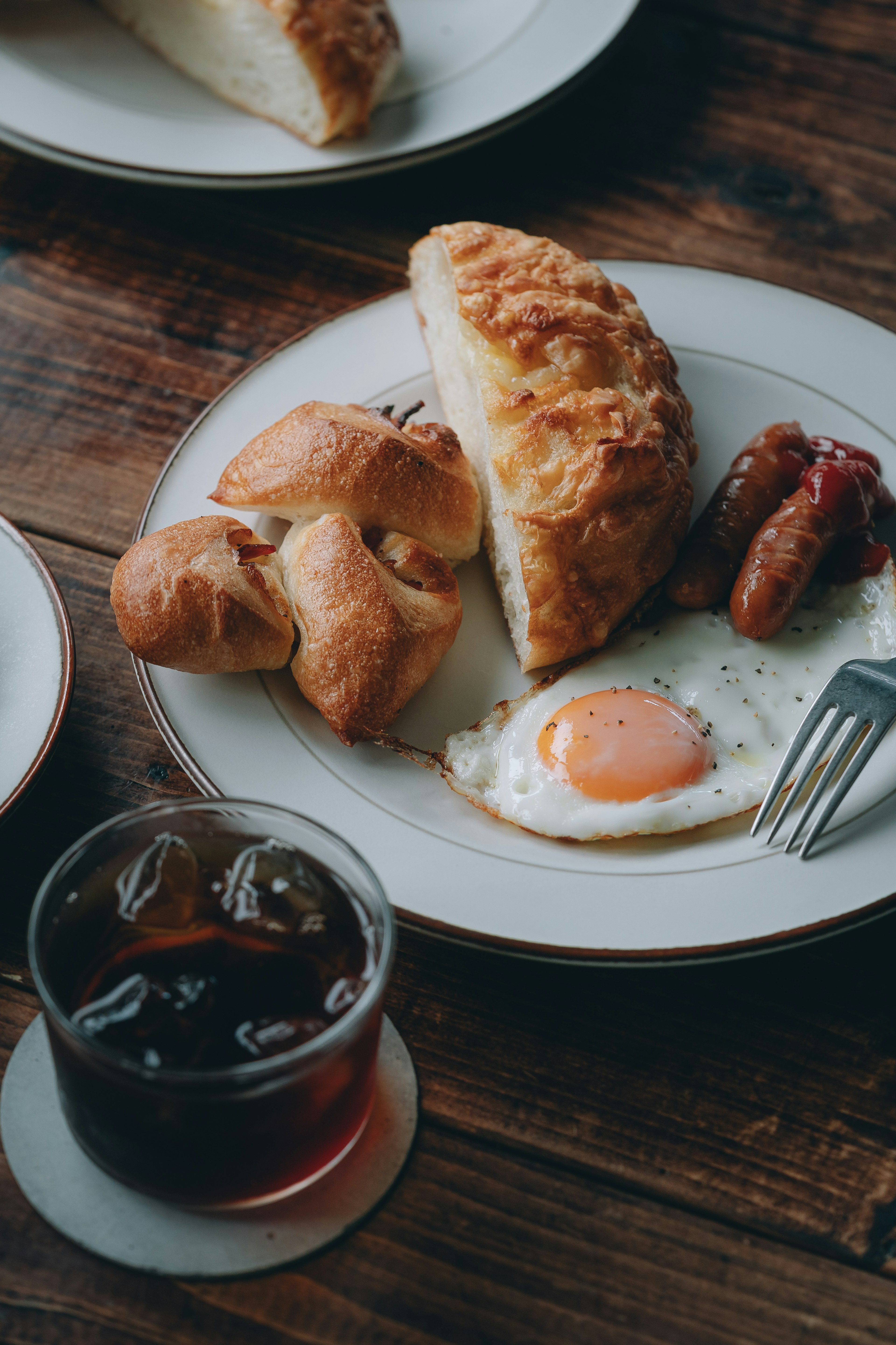 Breakfast plate featuring fried egg, sausages, and bread