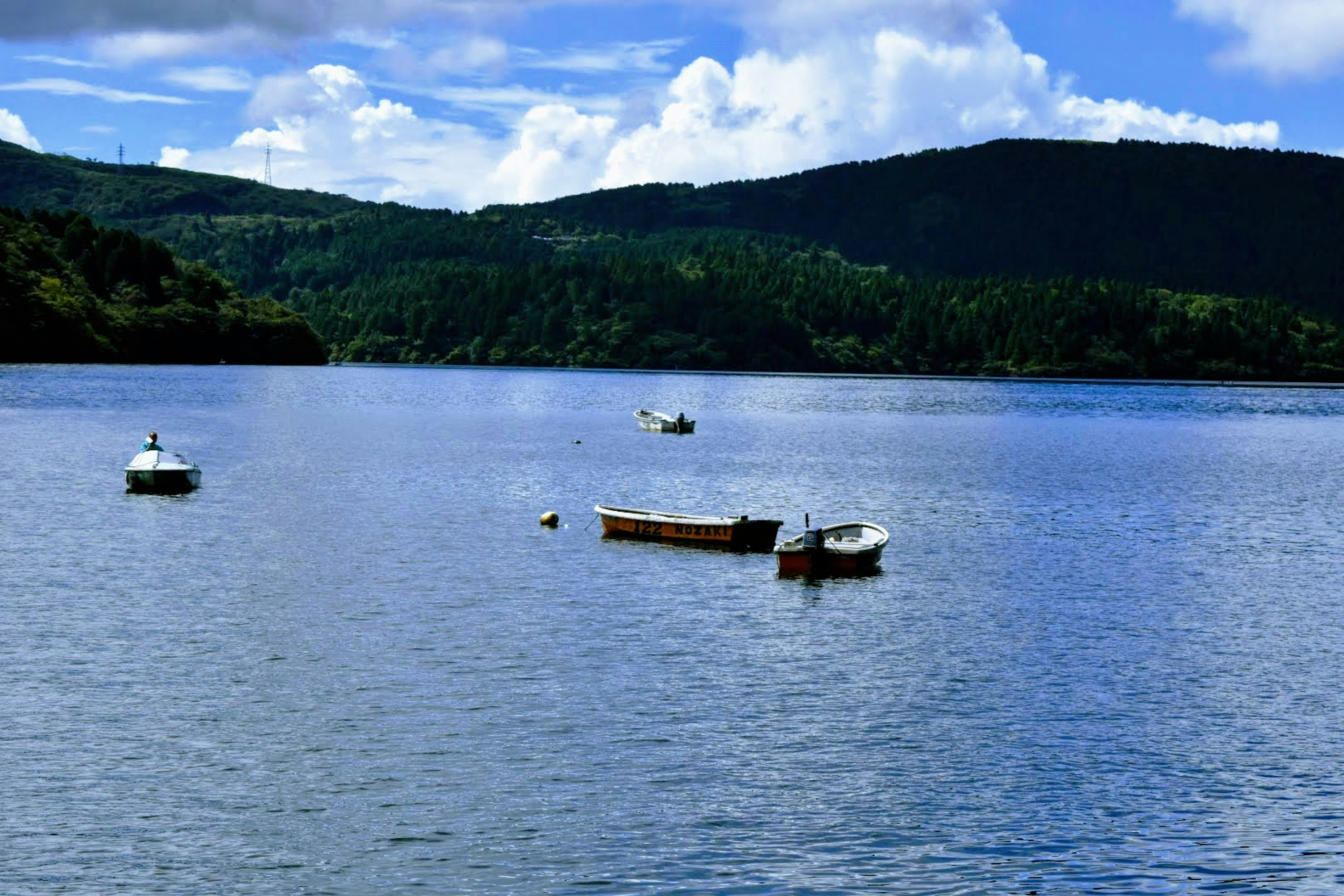 Scenic view of a blue lake with small boats and green hills