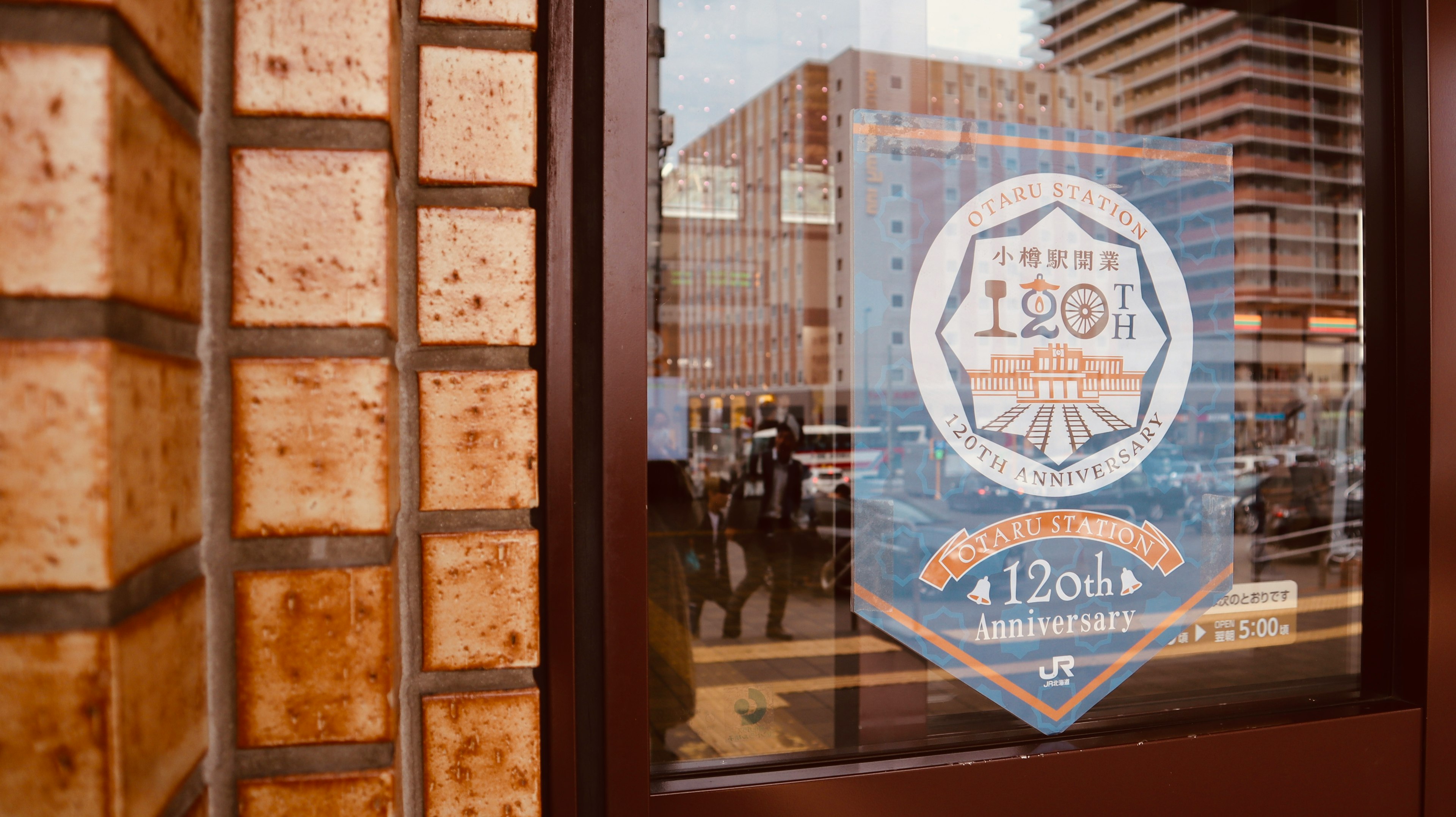 A window displaying a 120th anniversary badge with surrounding buildings reflected