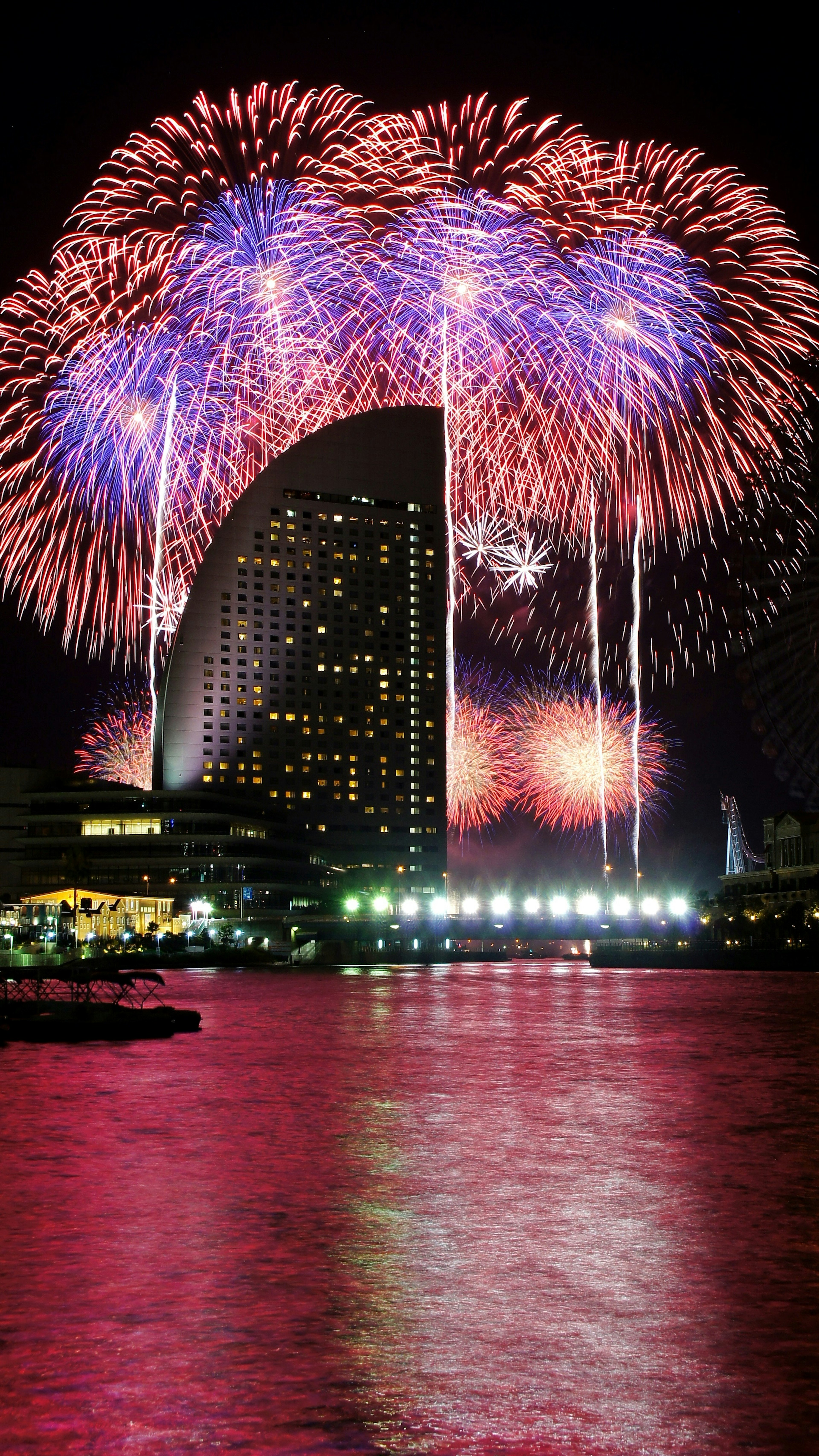 Fuochi d'artificio colorati che esplodono nel cielo notturno riflettendosi sull'acqua