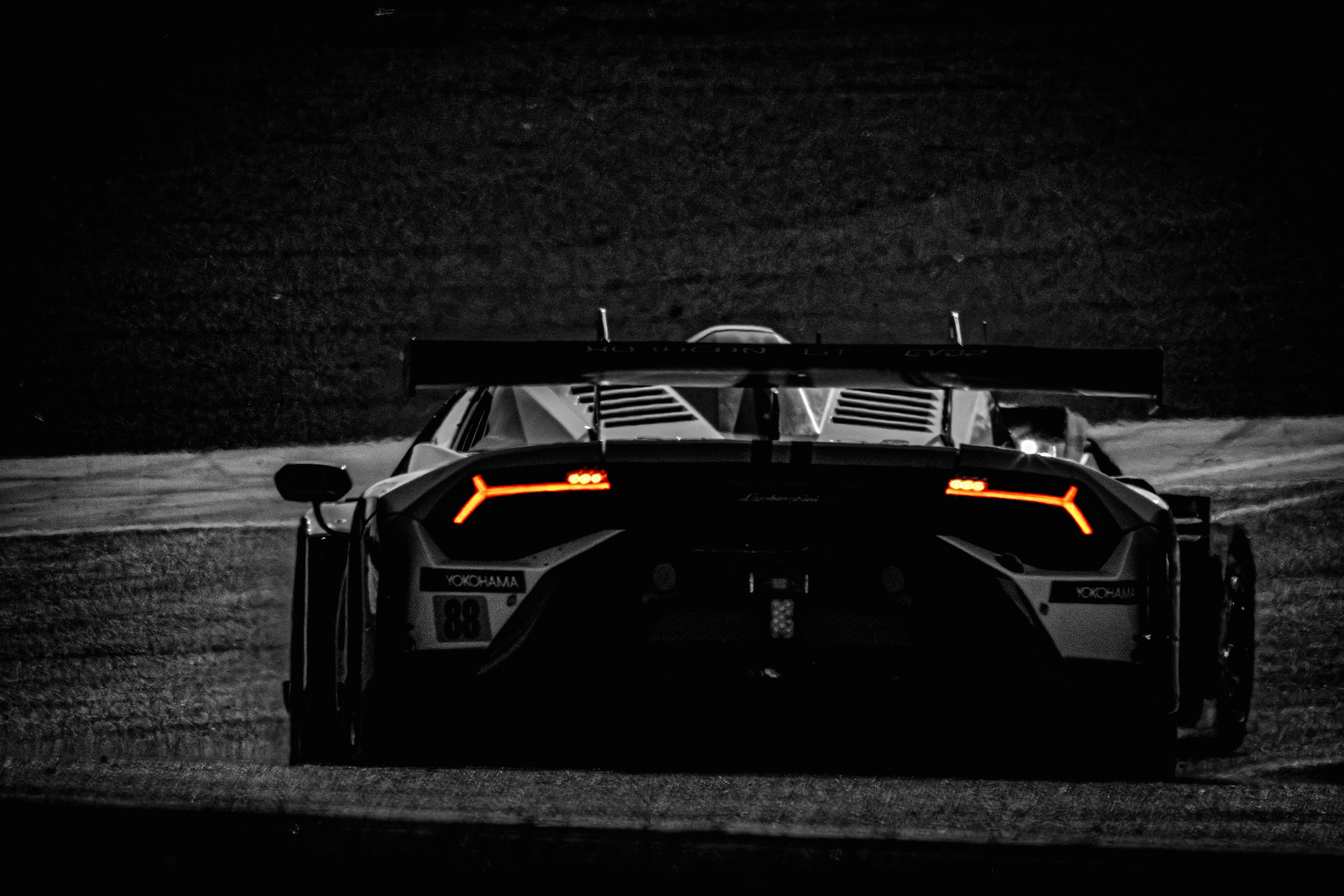 Rear view of a sleek sports car with distinctive orange tail lights against a dark background