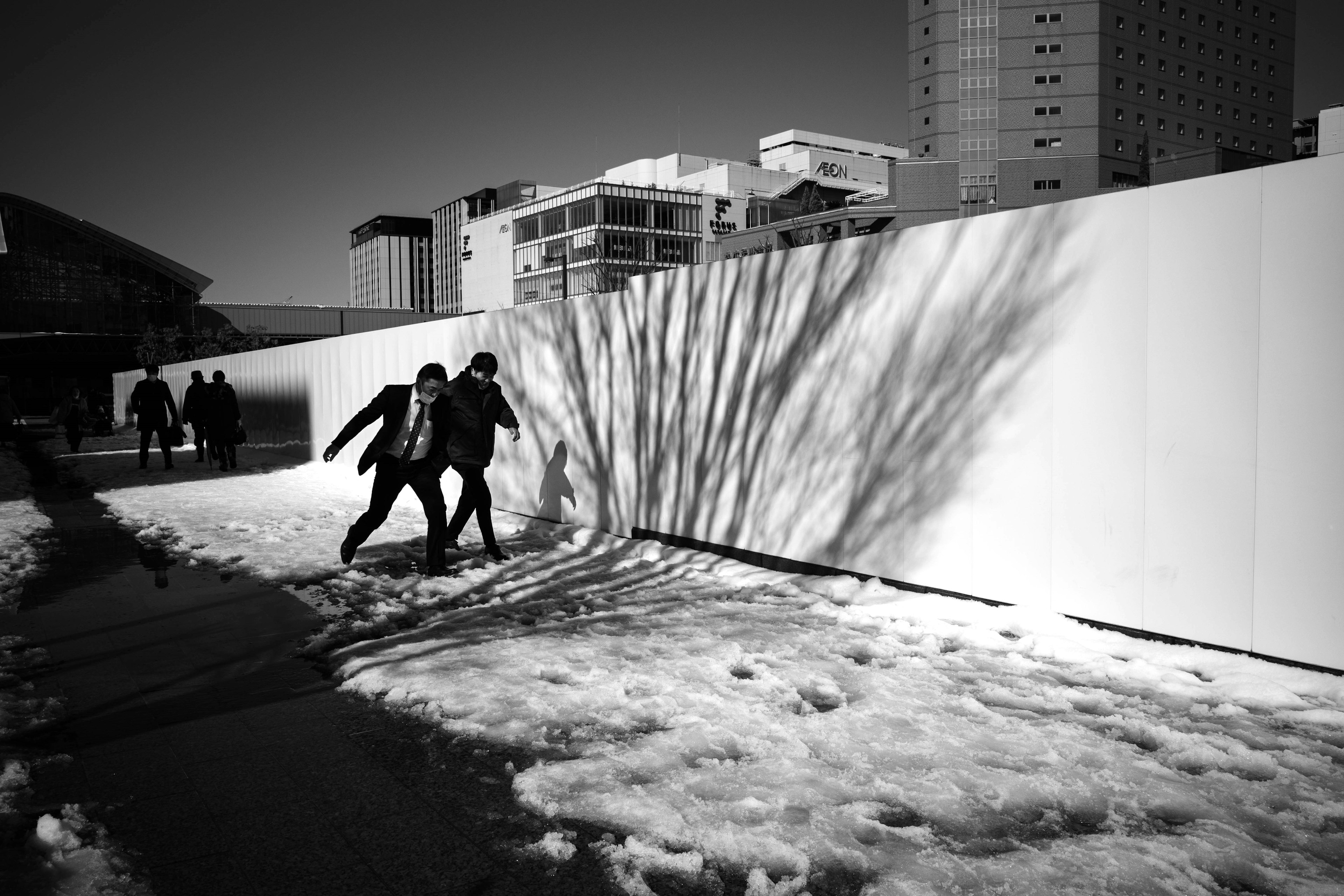 Due bambini che giocano sulla neve con ombre di edifici