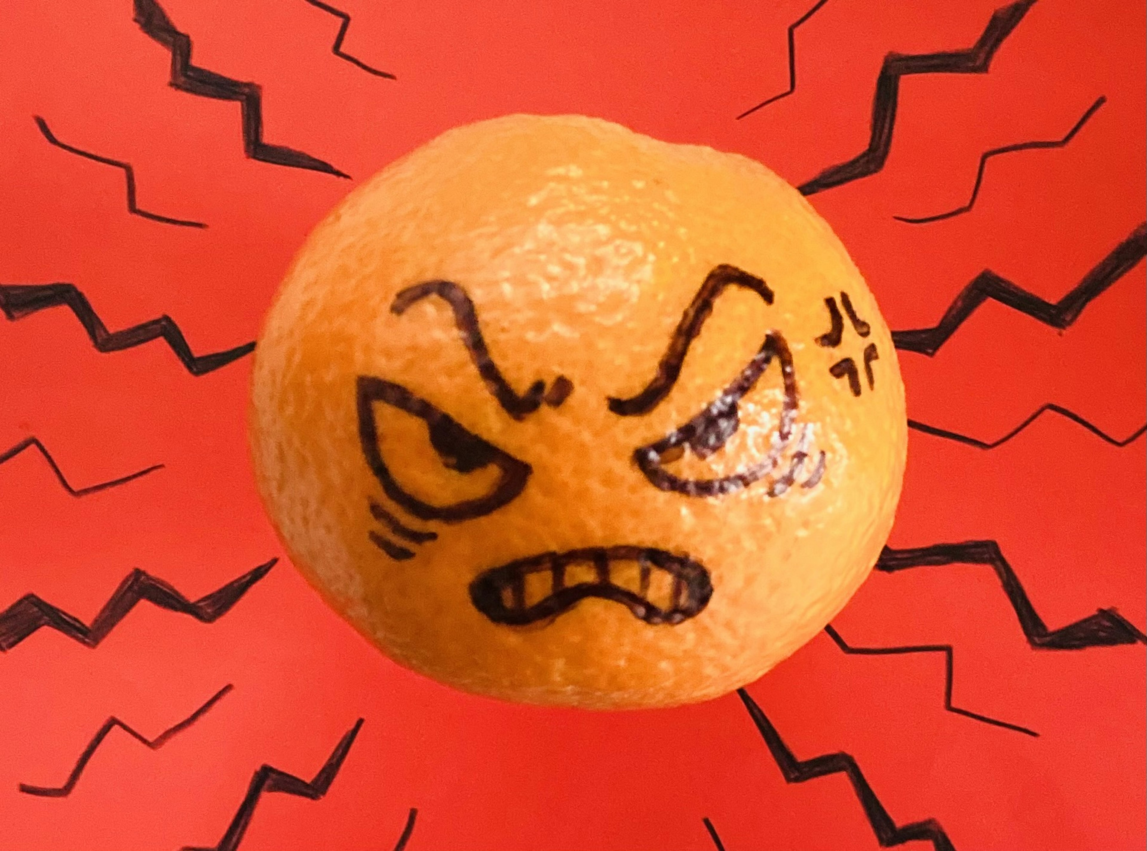 Angry orange fruit with facial expression against a red background