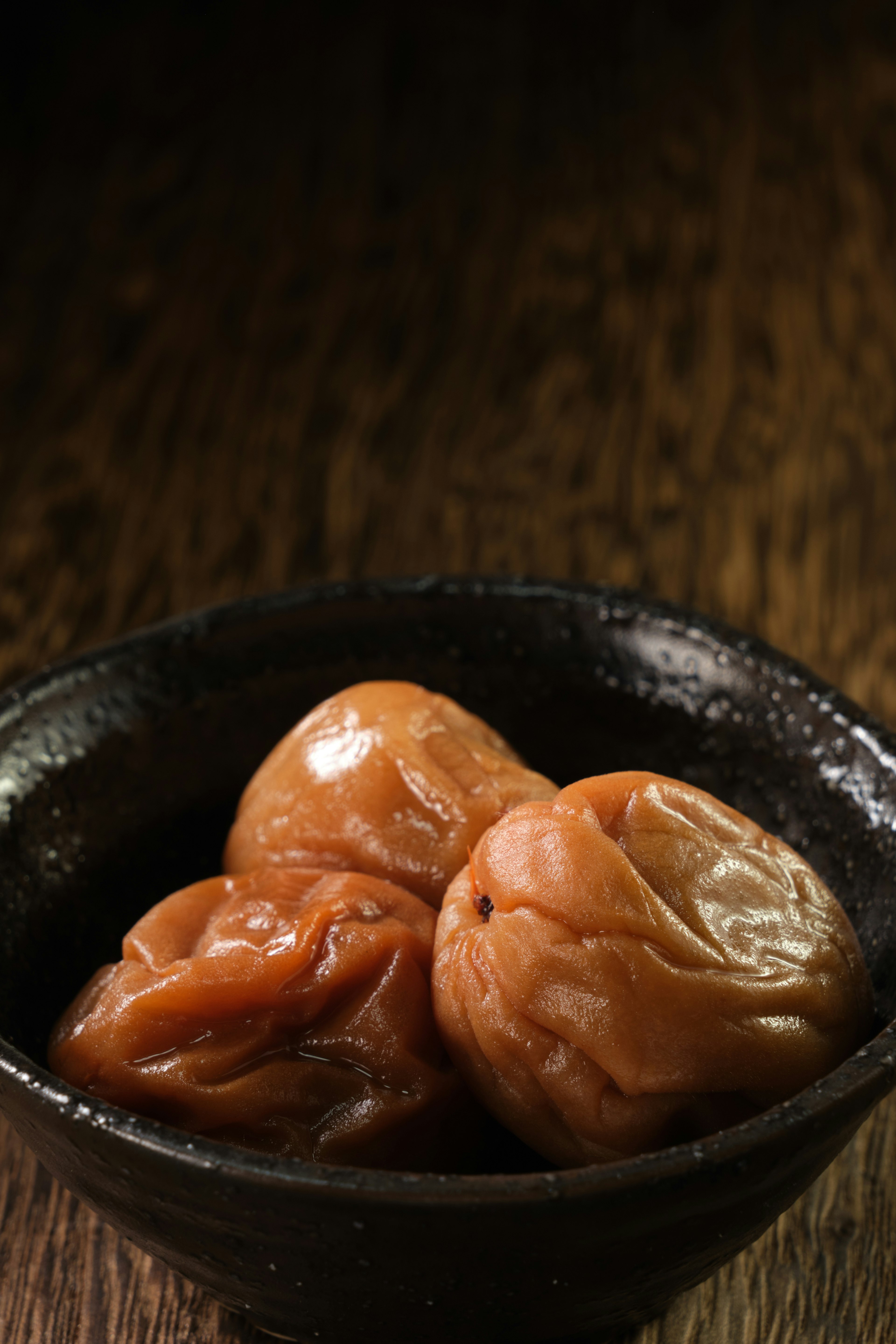 Image of pickled plums in a black bowl