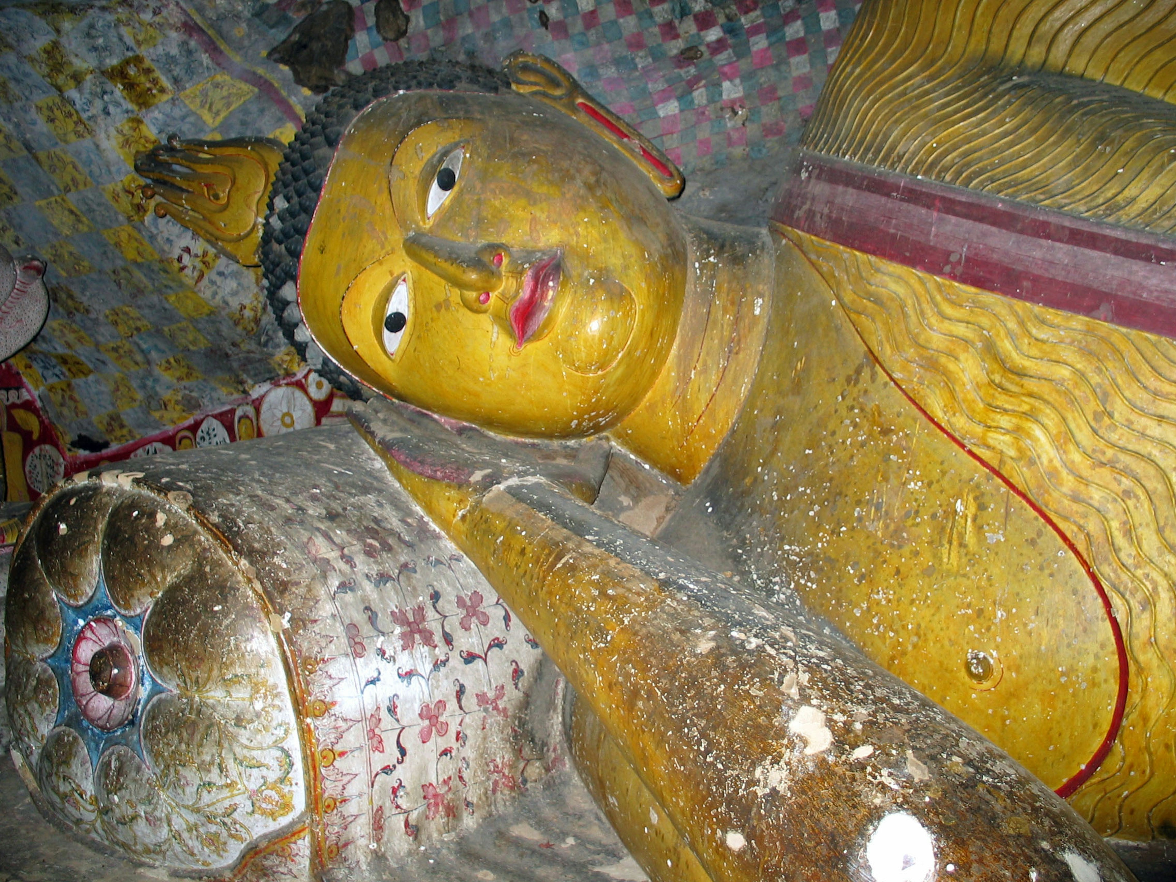 Dettaglio di una statua di Buddha dorata su un muro di grotta