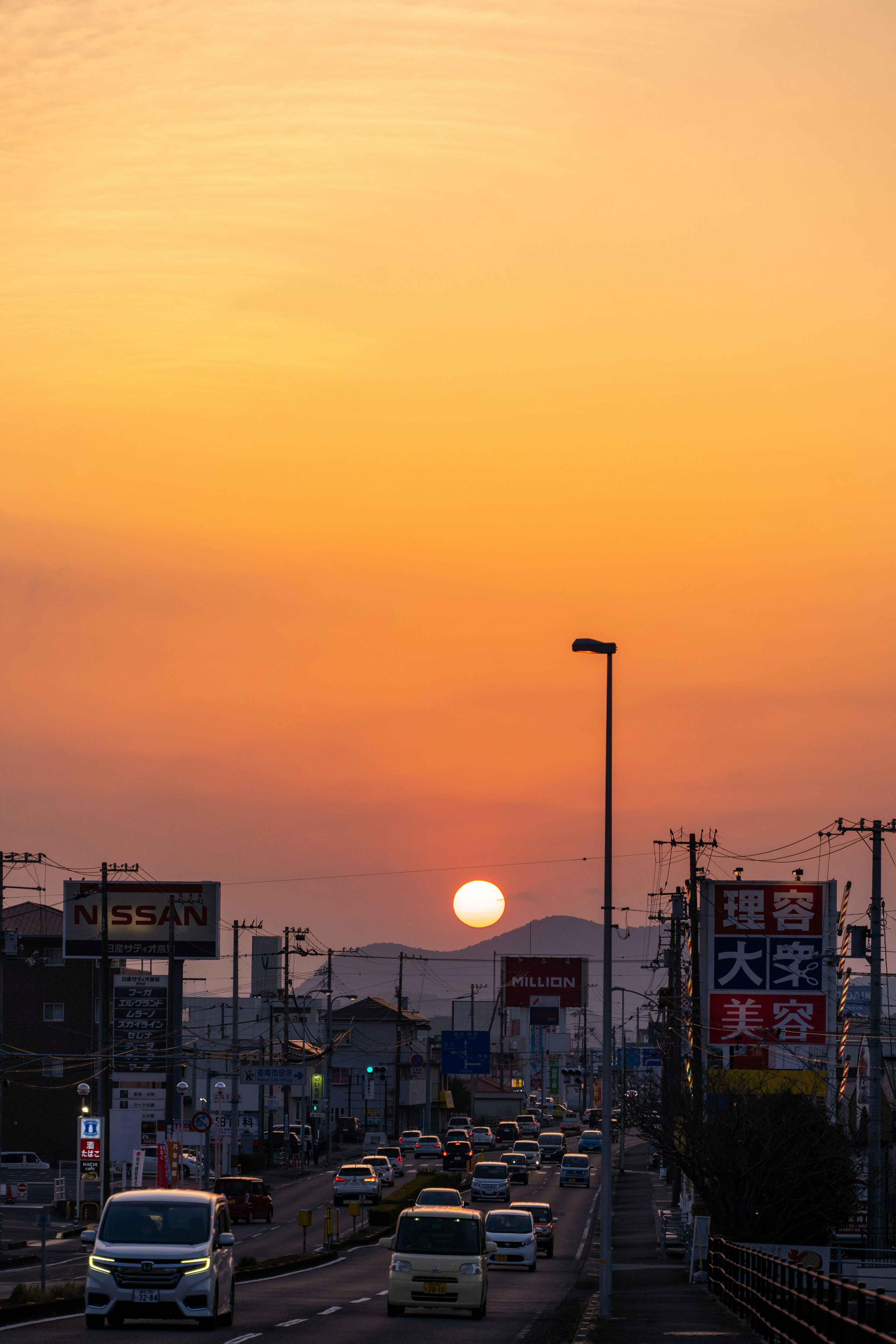 夕日が沈む街の風景　交通の様子と看板が見える