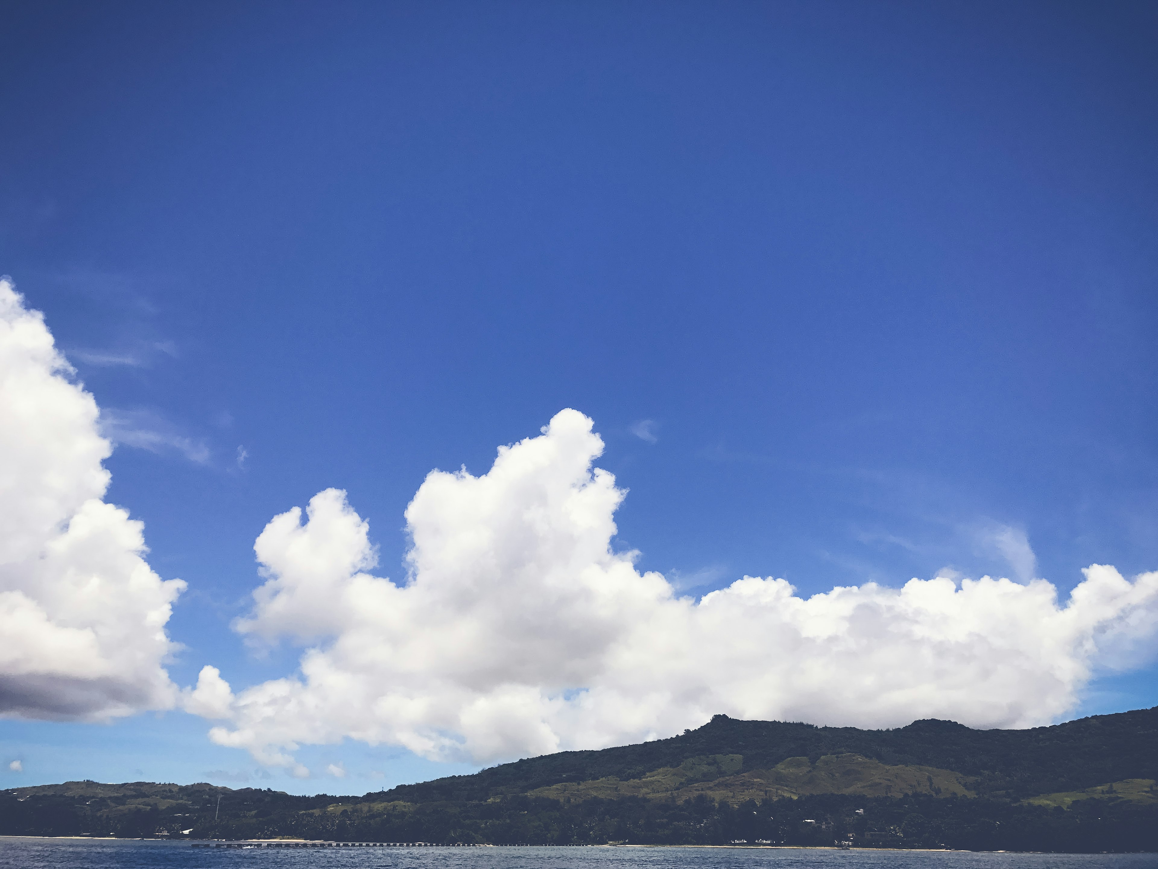 A scenic view of blue sky and white clouds with visible mountain outlines