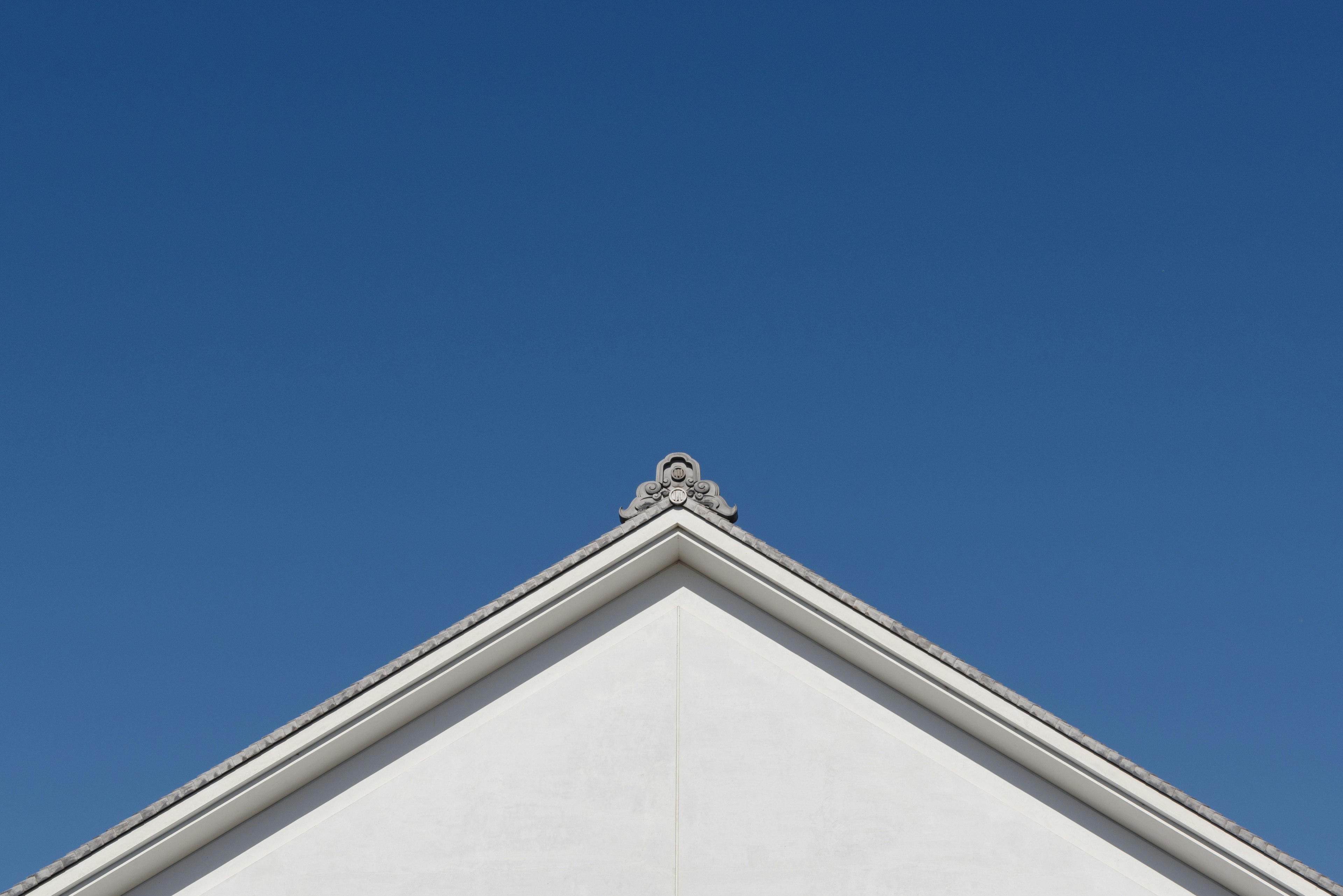 The tip of a white building roof under a blue sky