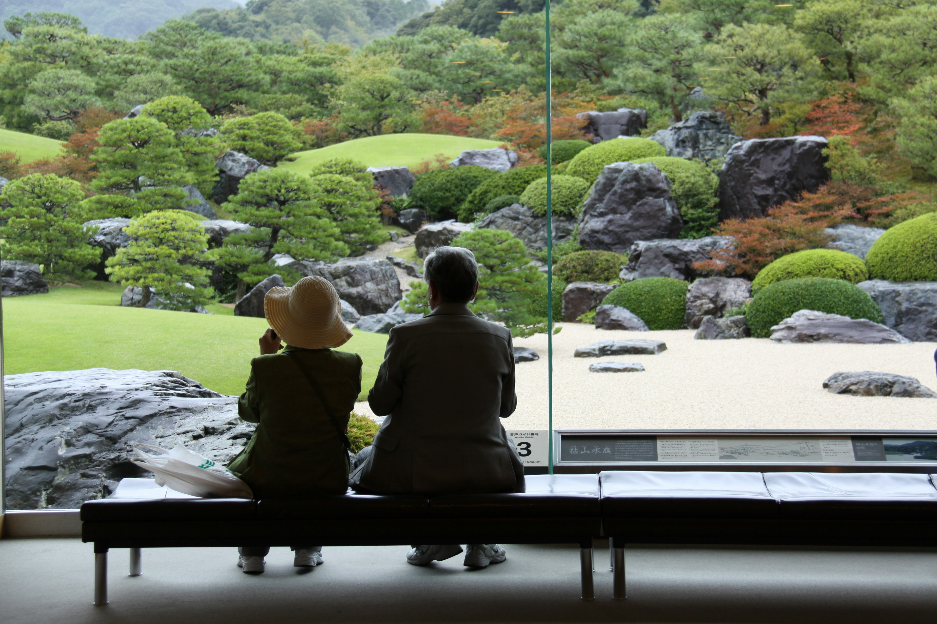 Dos personas sentadas contemplando un paisaje de jardín sereno