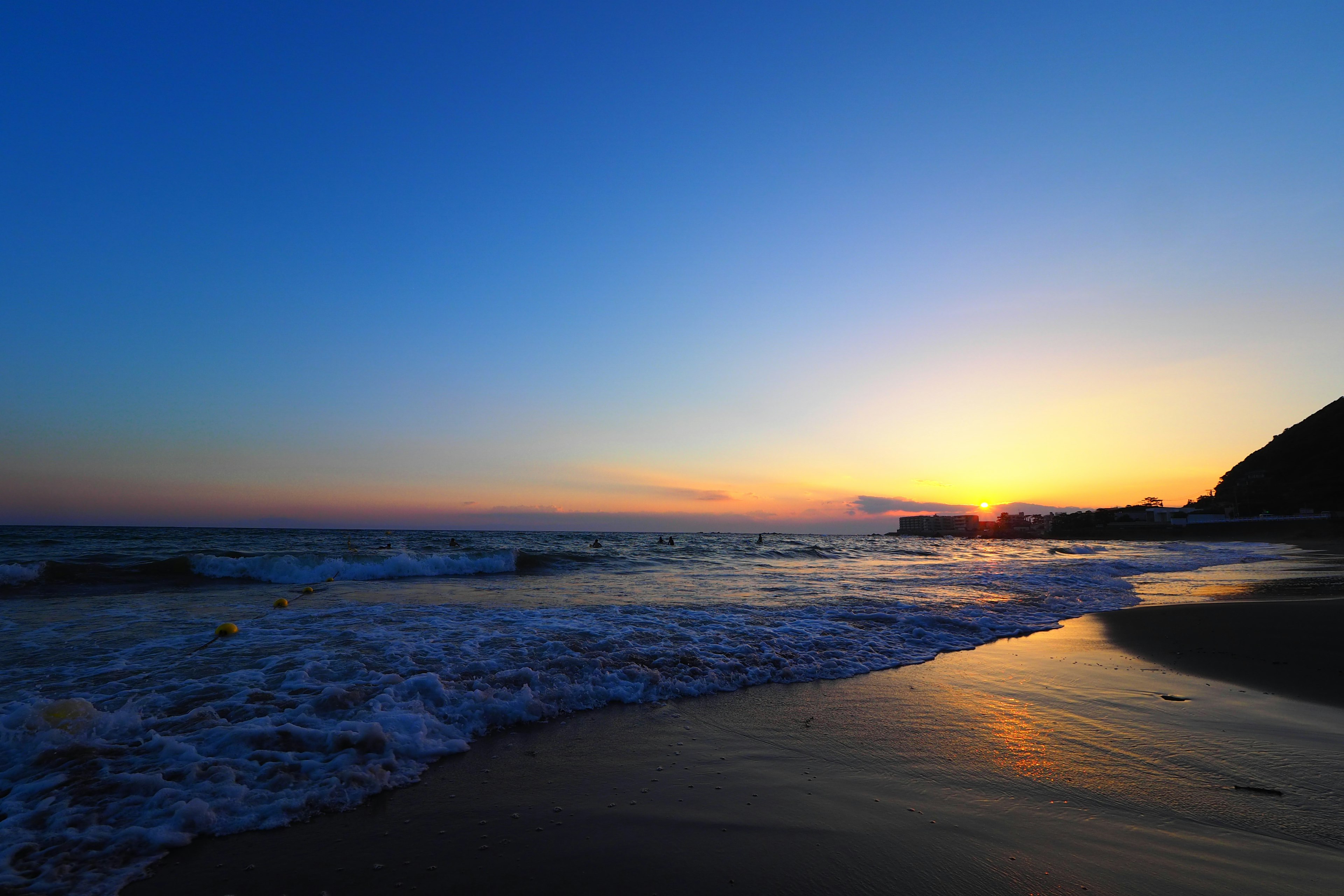 Vista panoramica di spiaggia con cielo blu e onde luce del tramonto che si riflette sull'acqua