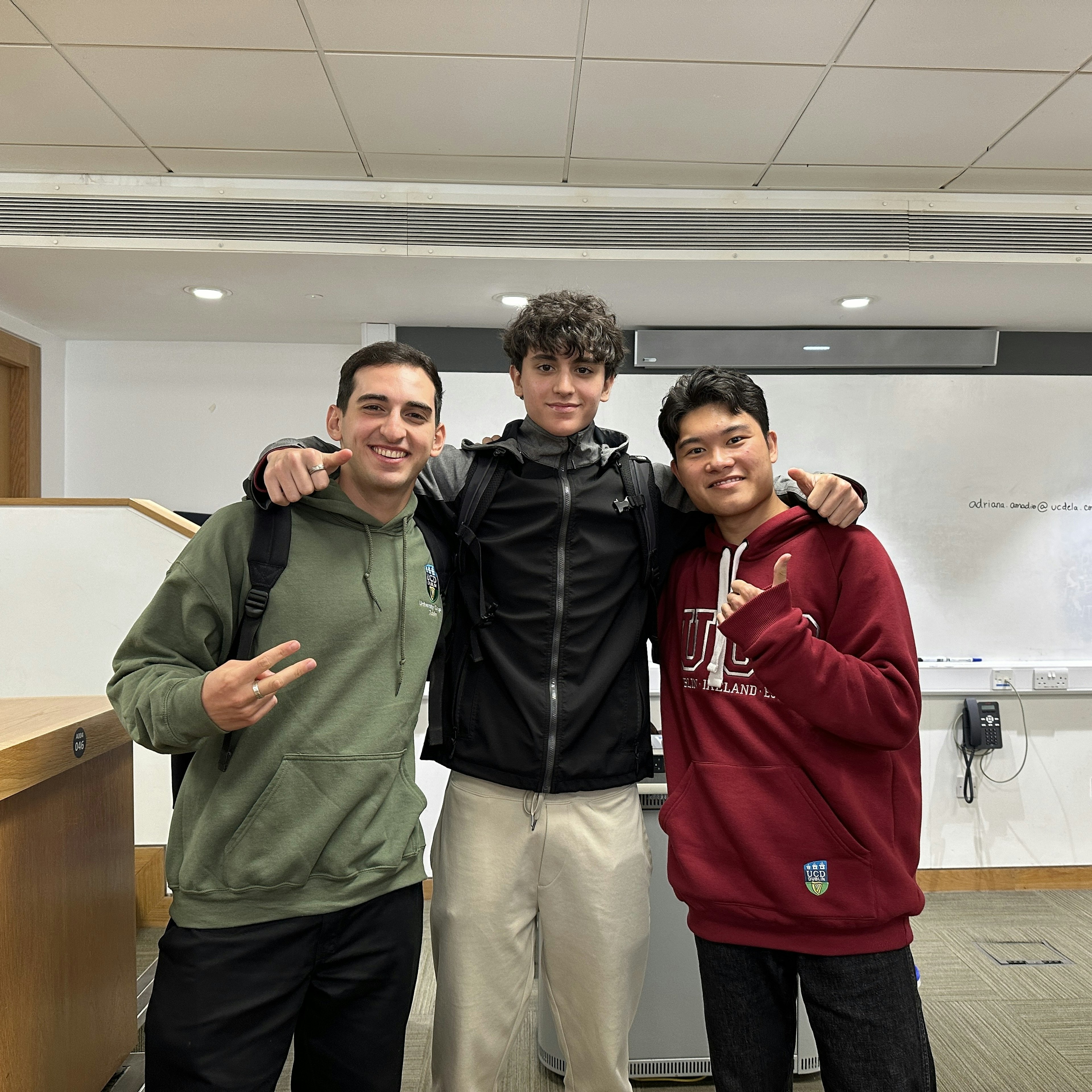 Trois étudiants posant ensemble dans une salle de classe