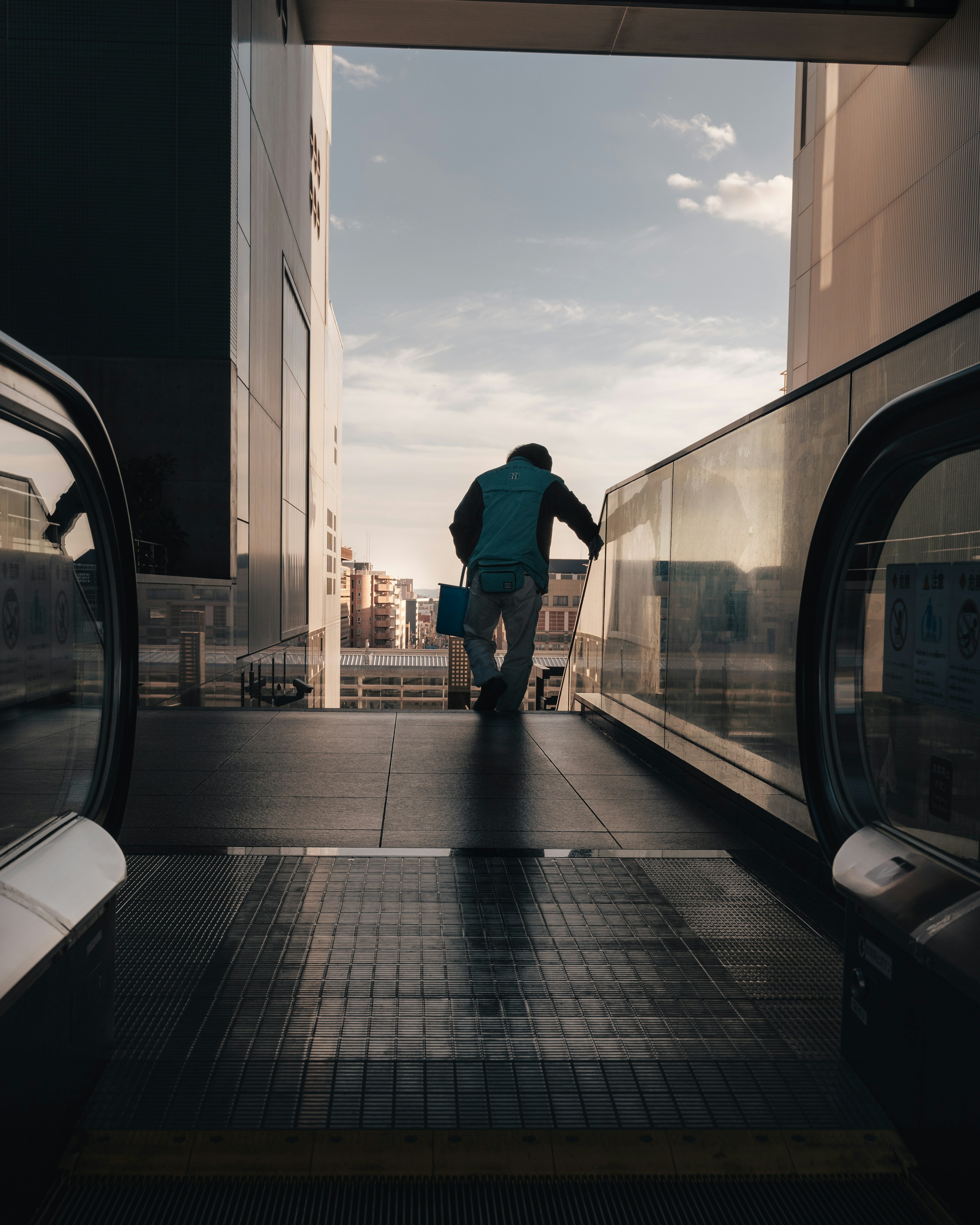 Silhouette of a man at the escalator exit with a cityscape in the background