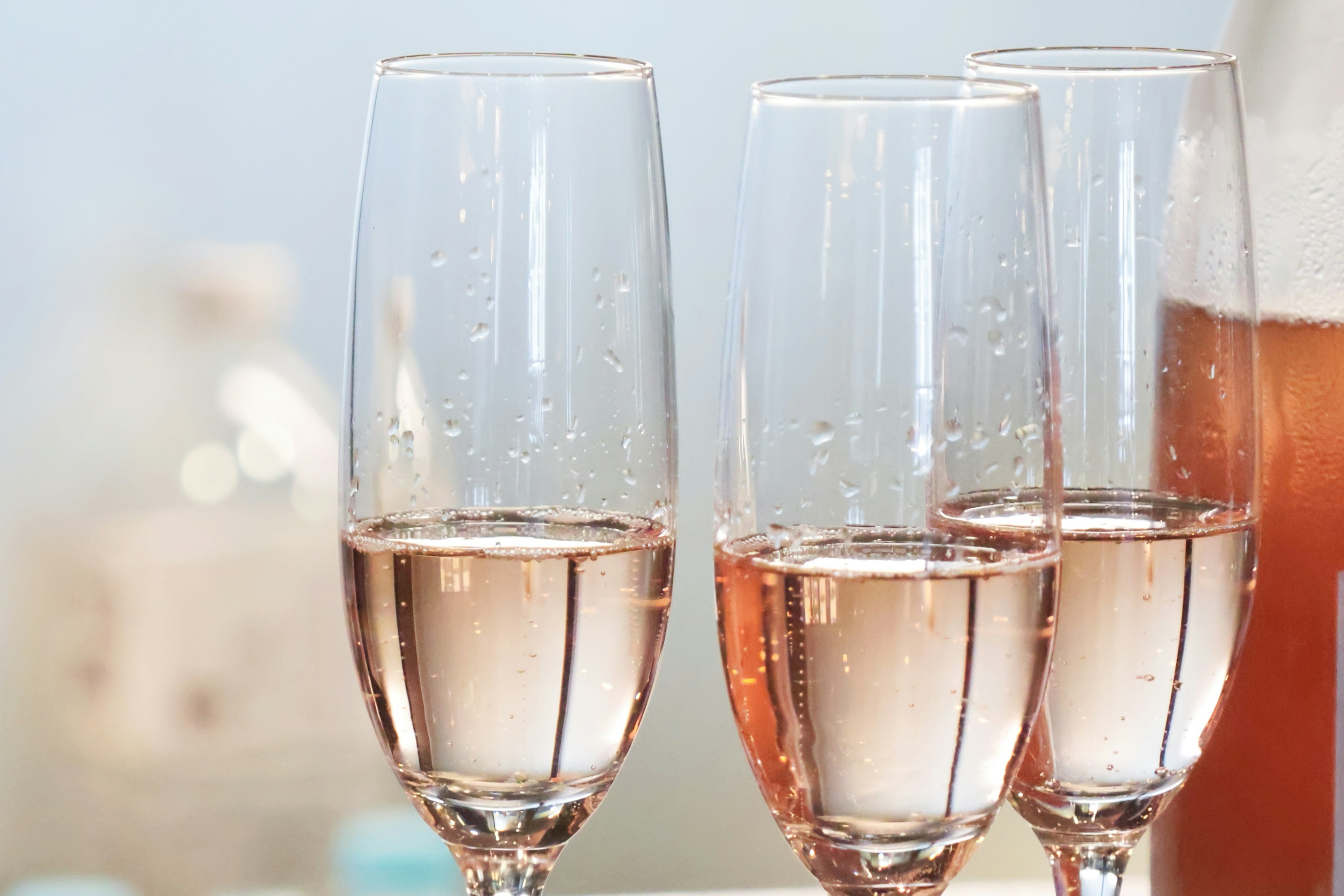 Three champagne glasses filled with sparkling rosé wine