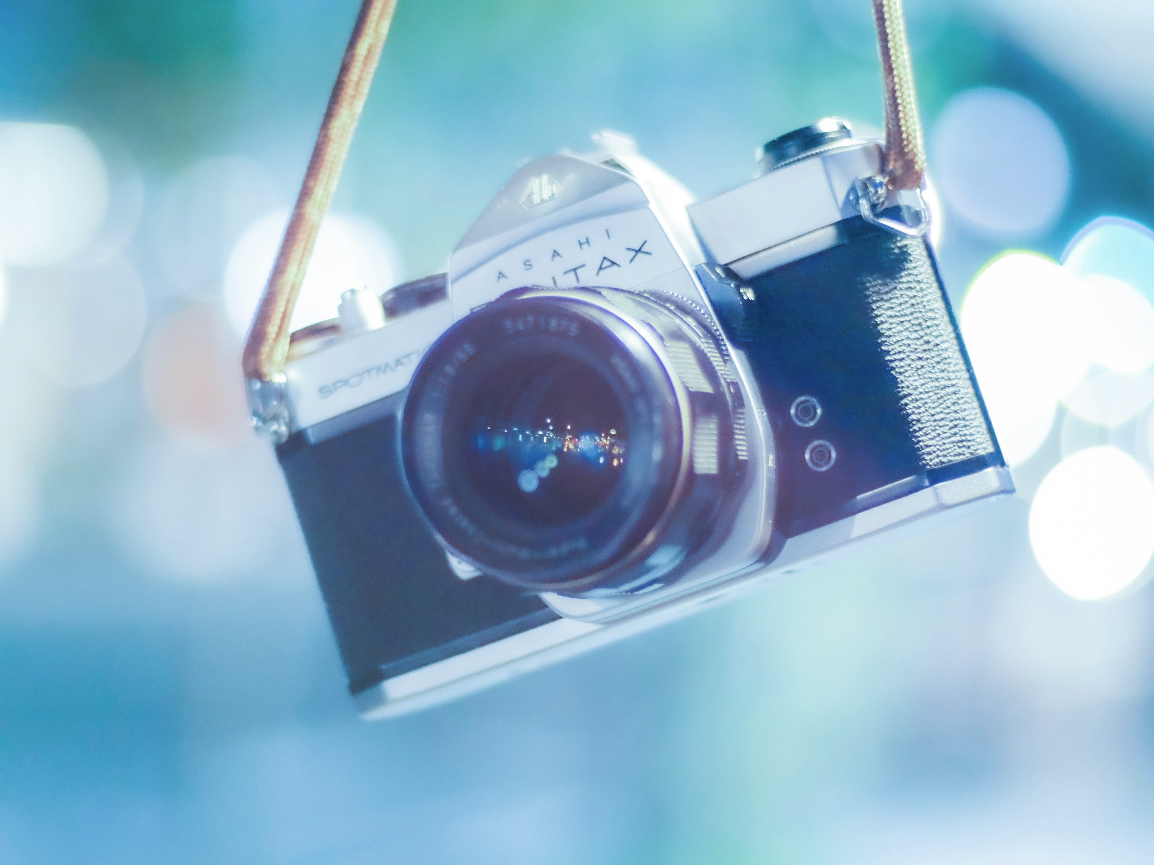 Un appareil photo vintage suspendu avec un fond lumineux bleu flou