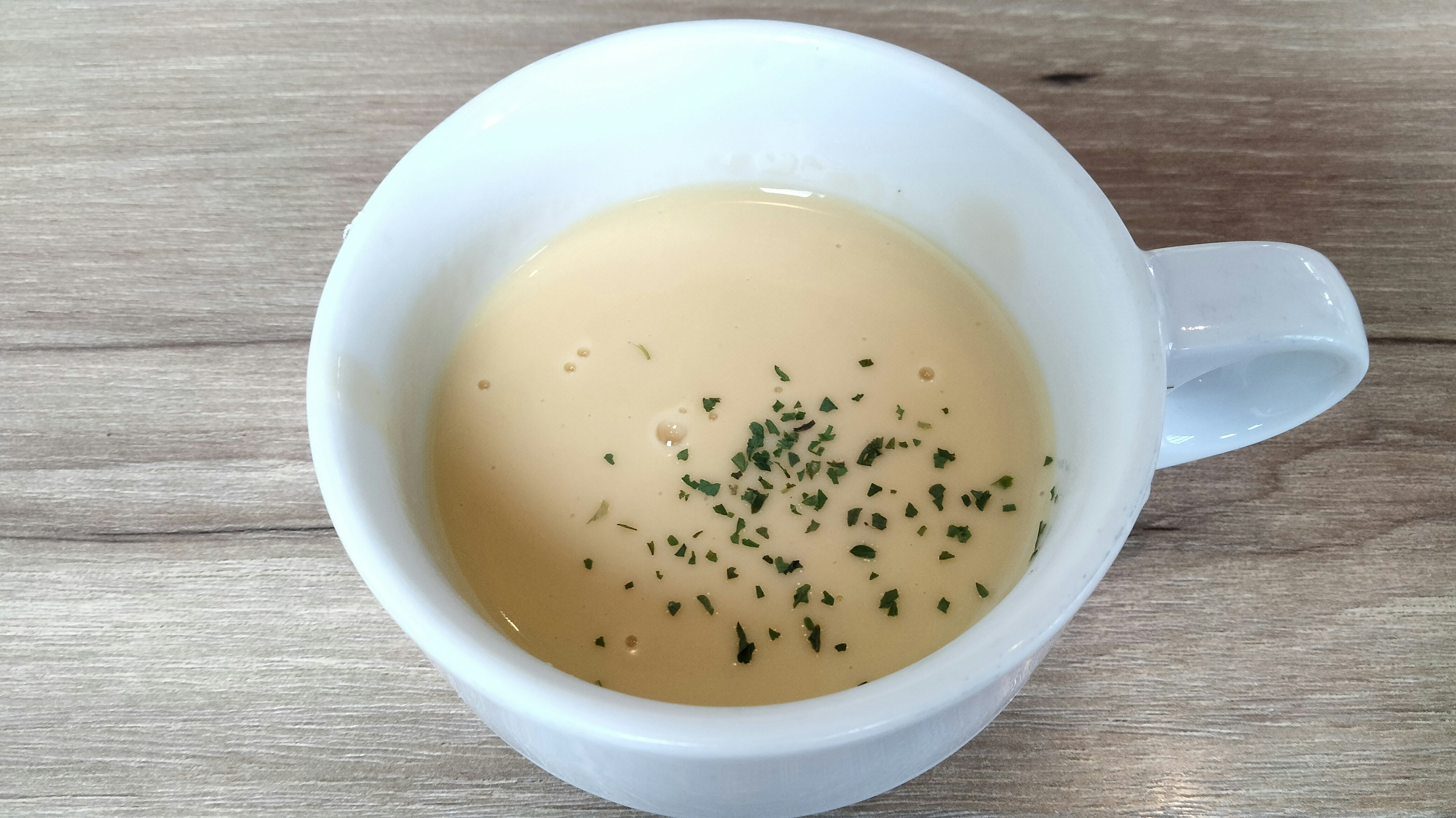 Zuppa cremosa in una tazza bianca guarnita con prezzemolo