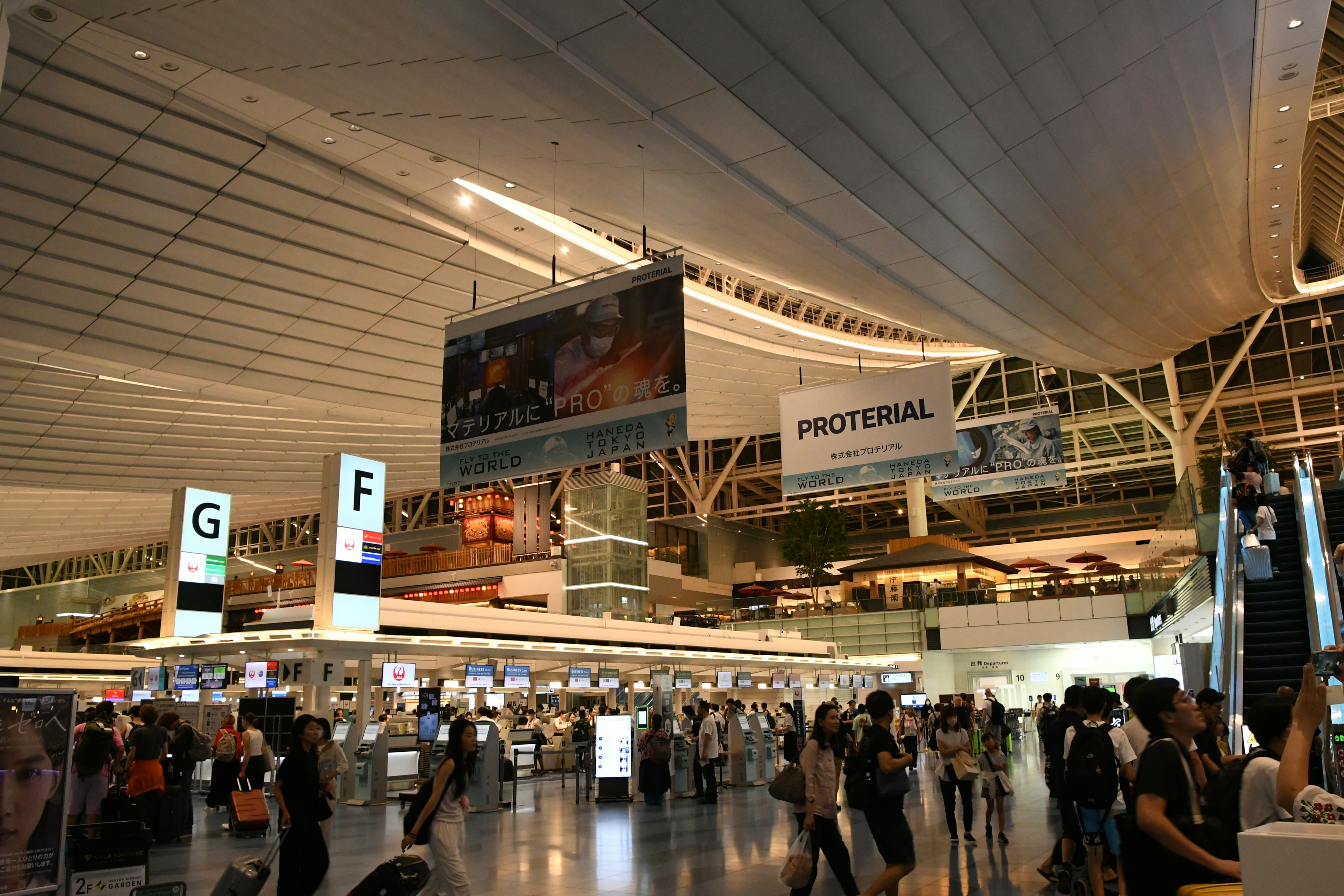 Spacious interior of an airport with many people and large advertising banners