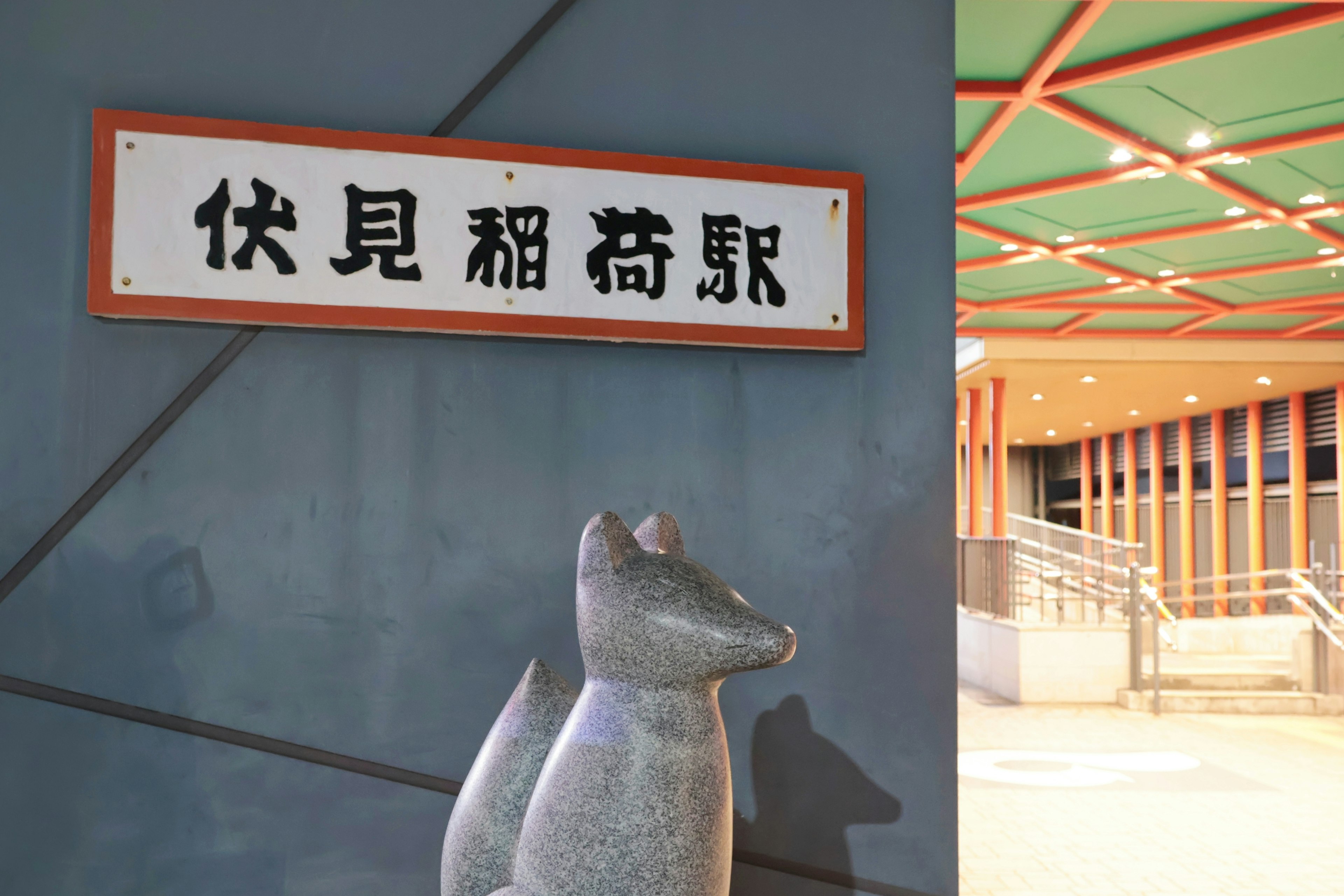 A station sign and a fox sculpture in a modern setting