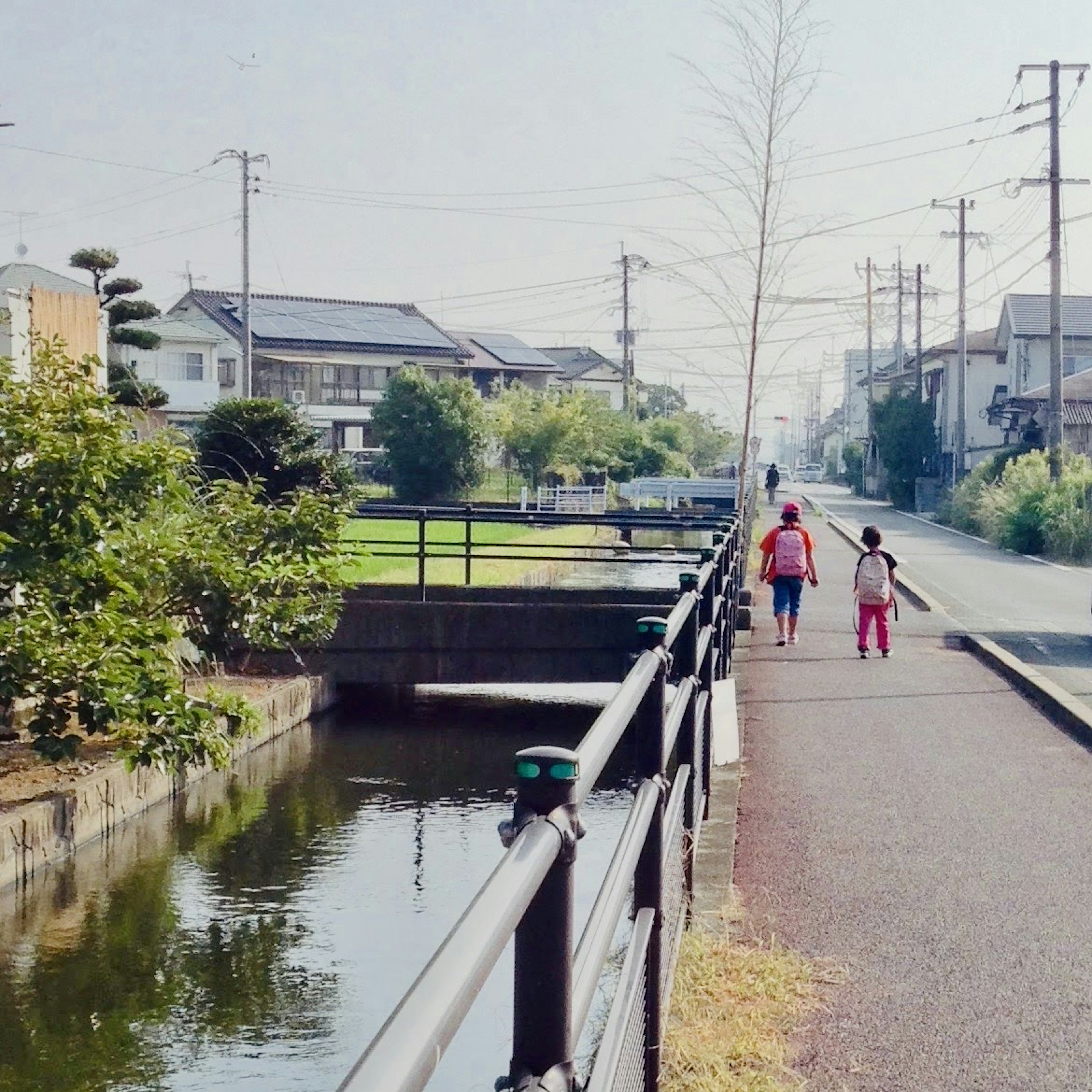 Silhouette of a parent and child walking along a riverbank in a serene setting