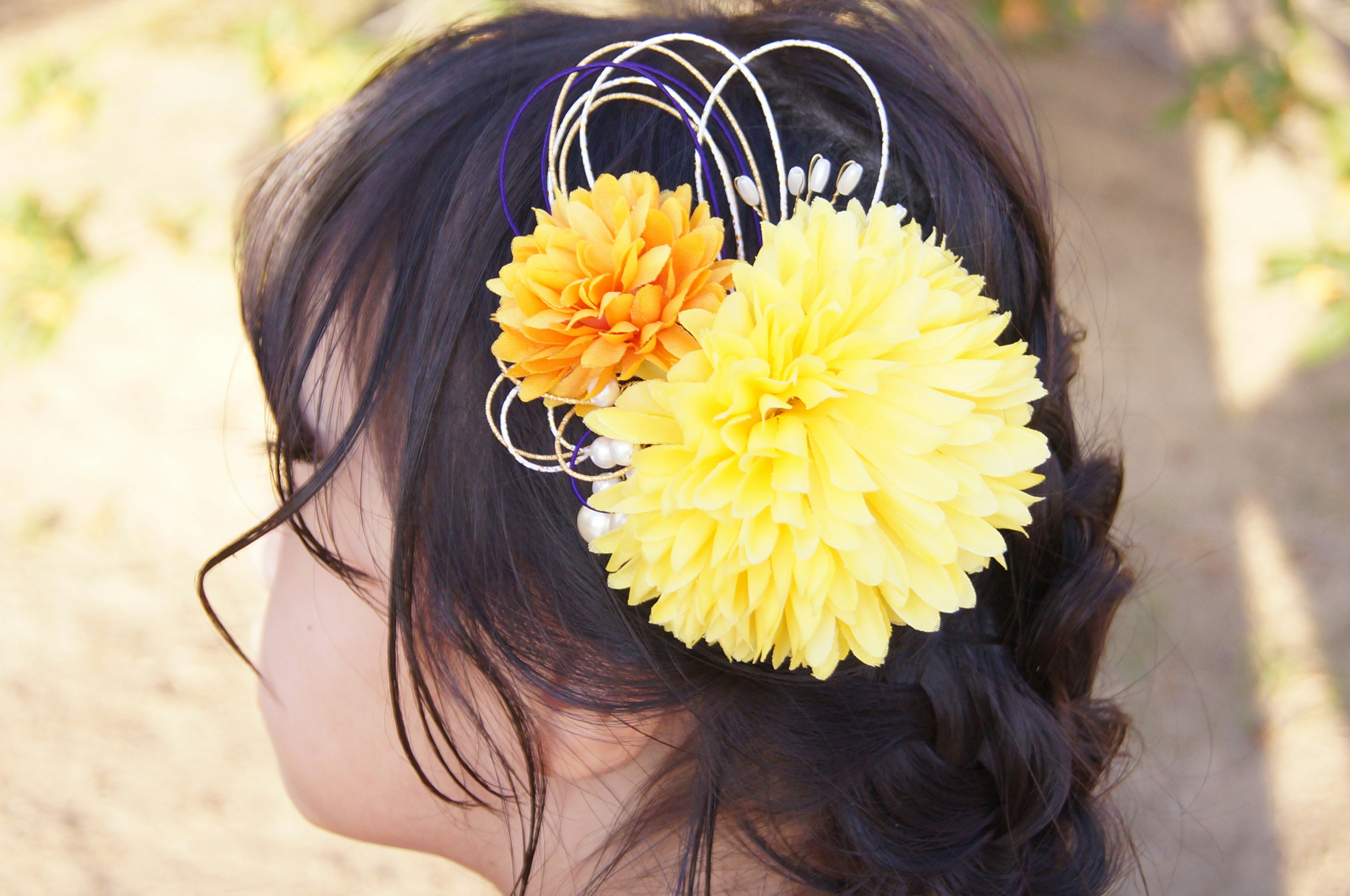 A woman's profile with yellow and orange flower hair accessories