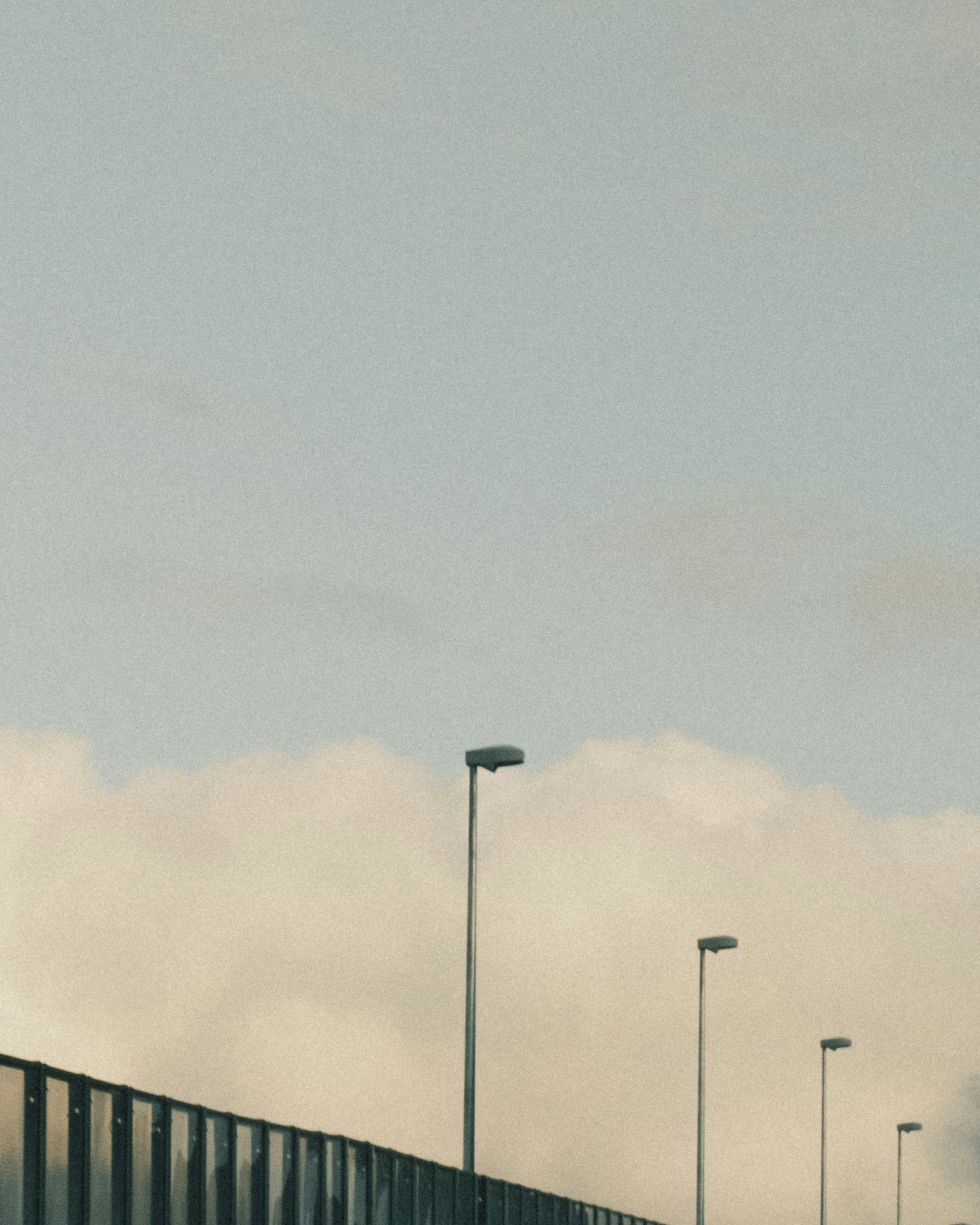 A view of streetlights against a blue sky with clouds