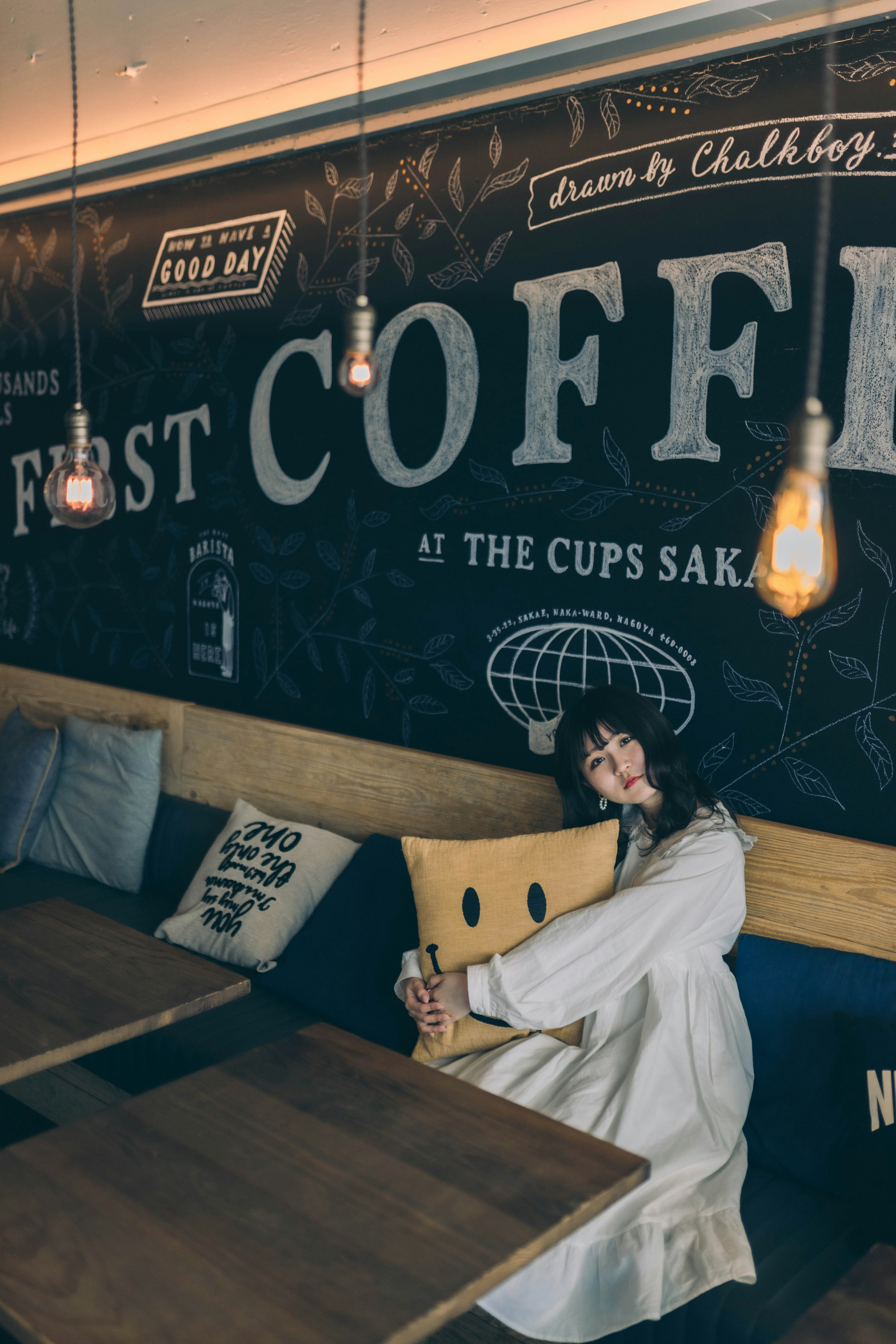 Eine Frau umarmt ein Kissen in einem Café mit Wandkunst zum Thema Kaffee