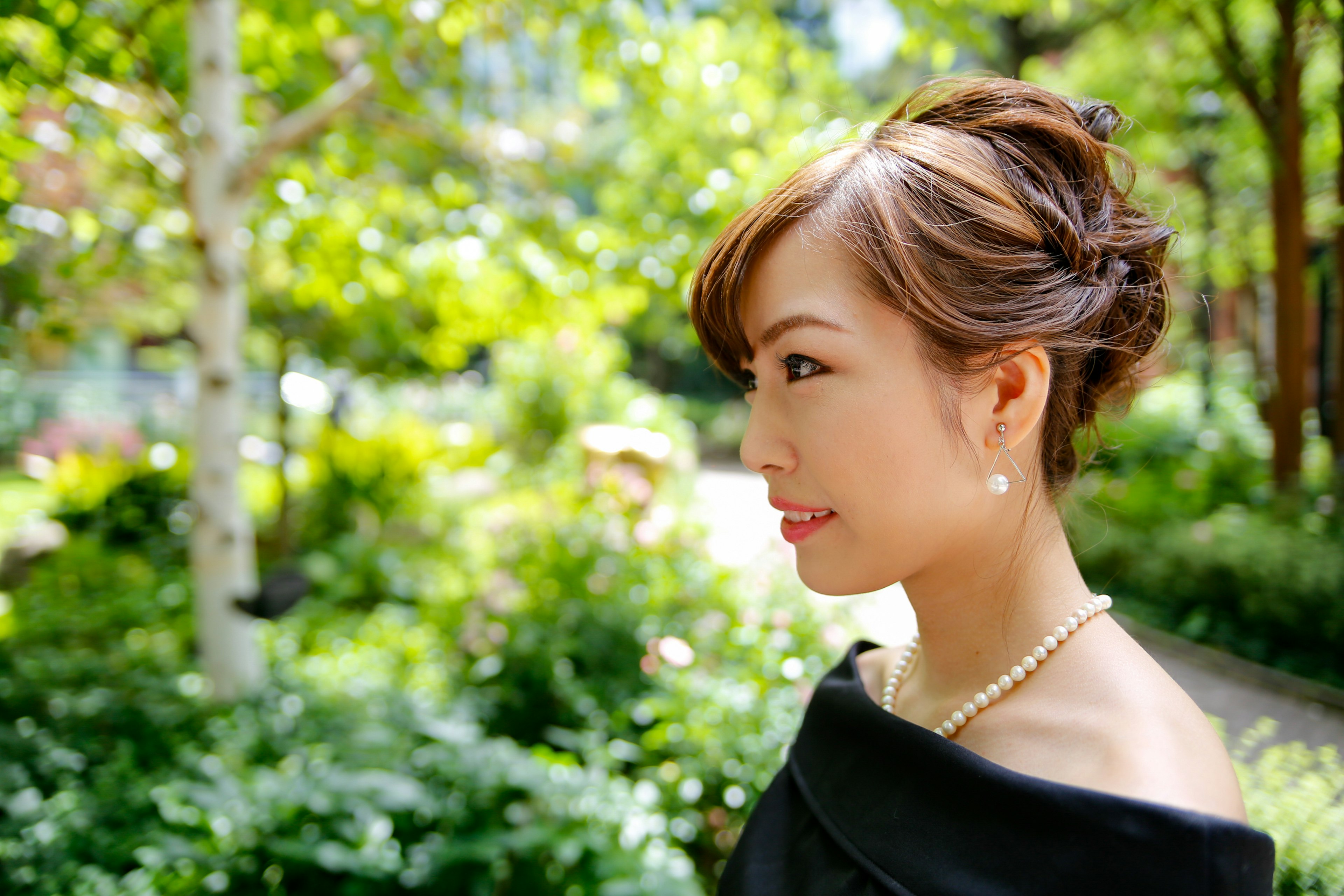 Portrait of a woman standing sideways in a lush green background