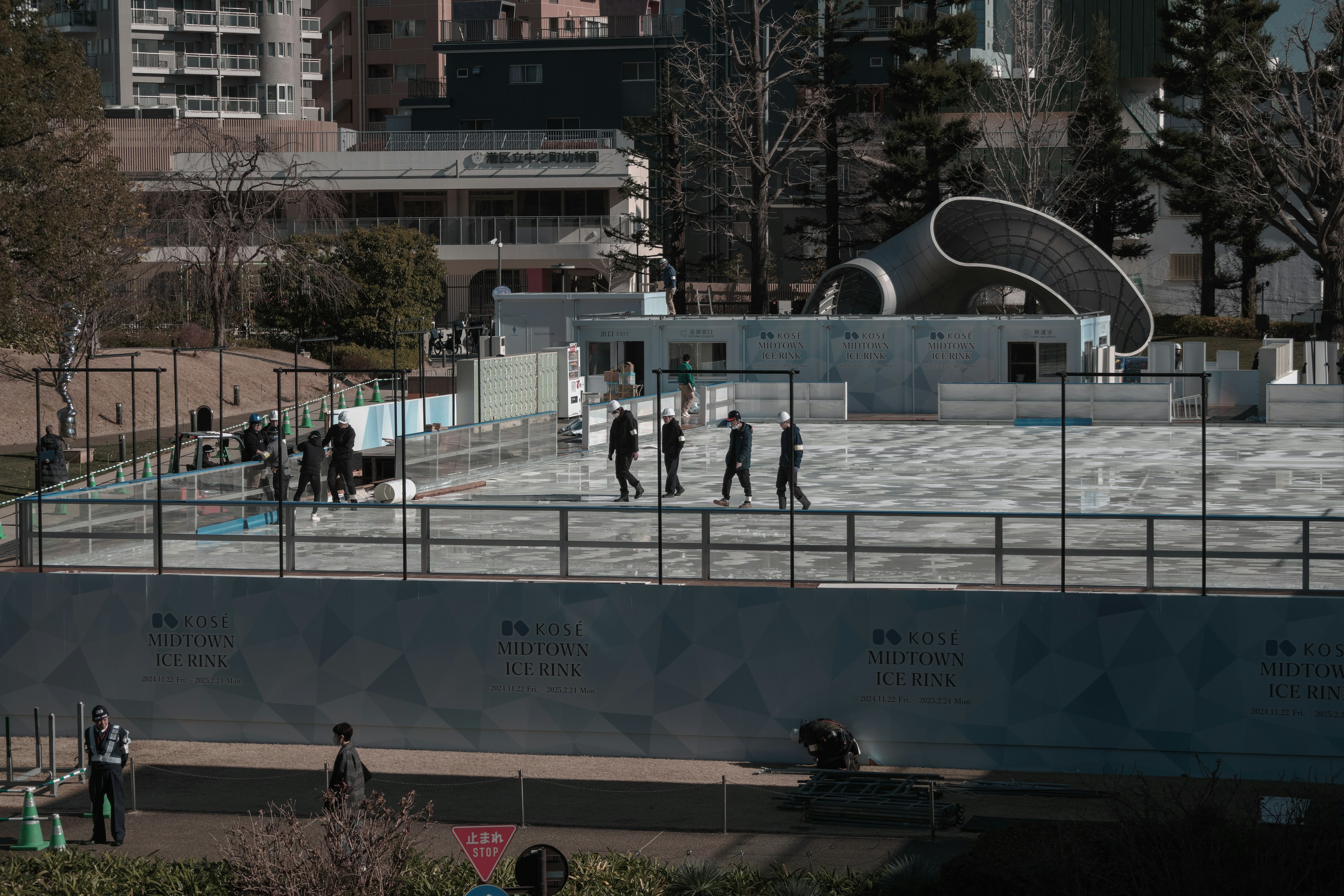 People working in a park area with a modern architectural structure