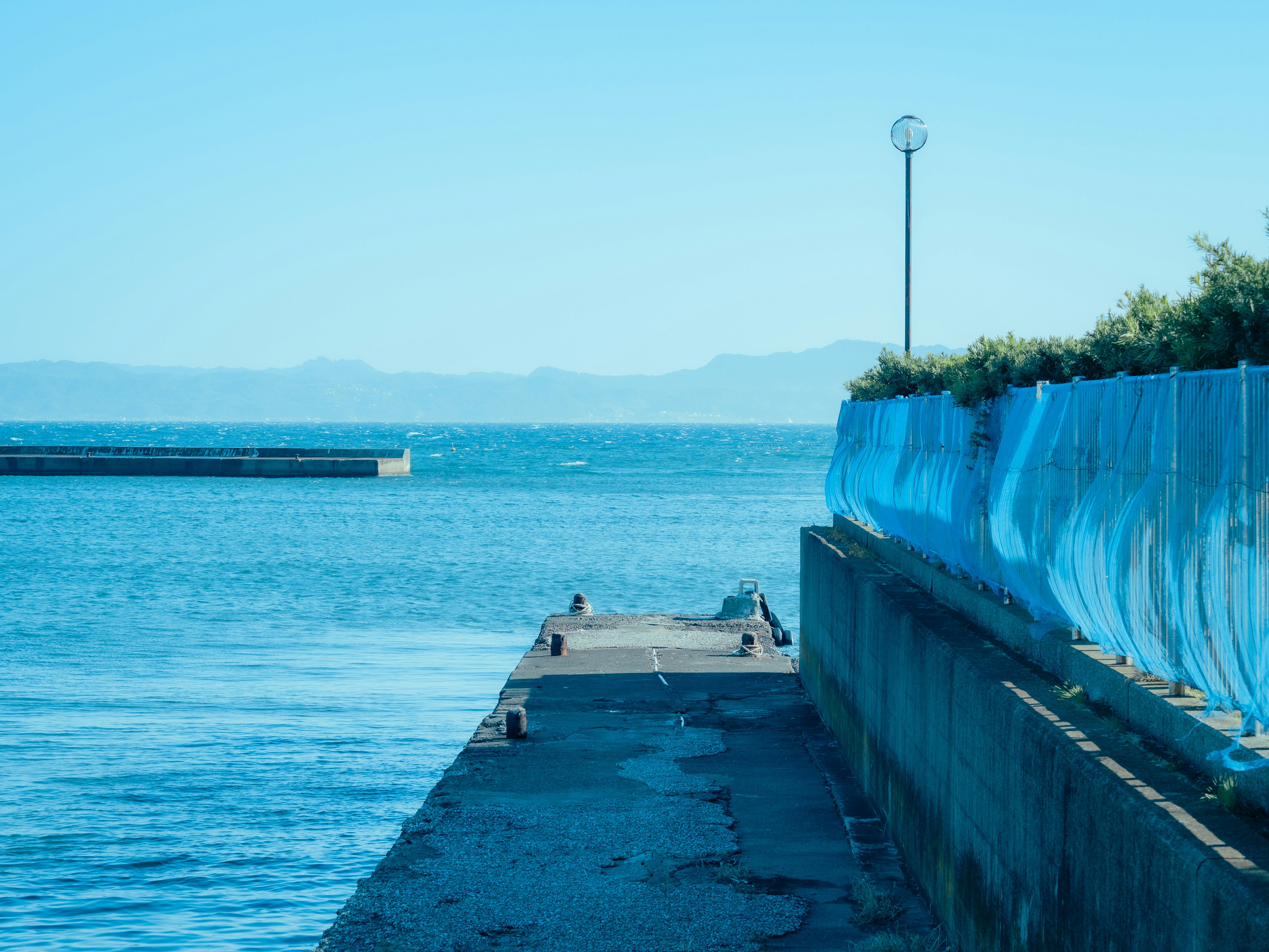 Malersicher Blick auf das blaue Meer und den Pier Heller Himmel und ruhige Wasseroberfläche