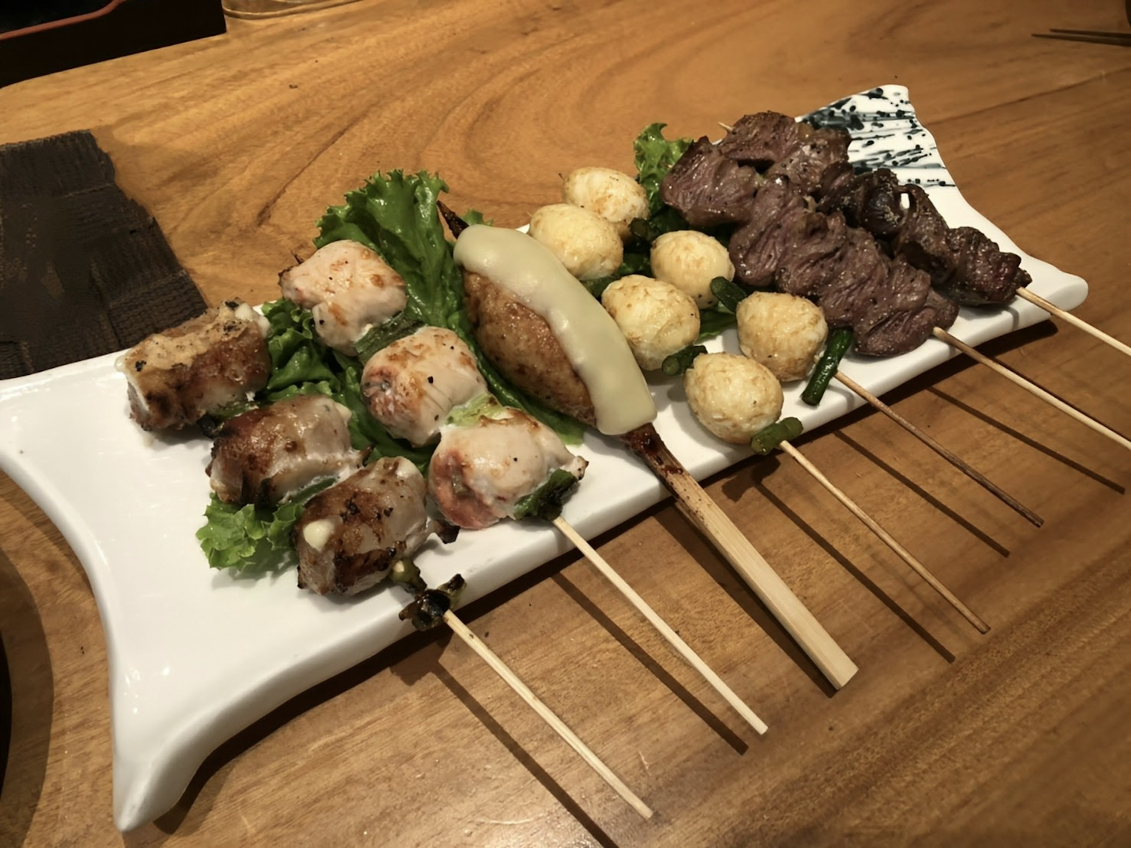 Brochetas a la parrilla y ensalada dispuestas en un plato blanco