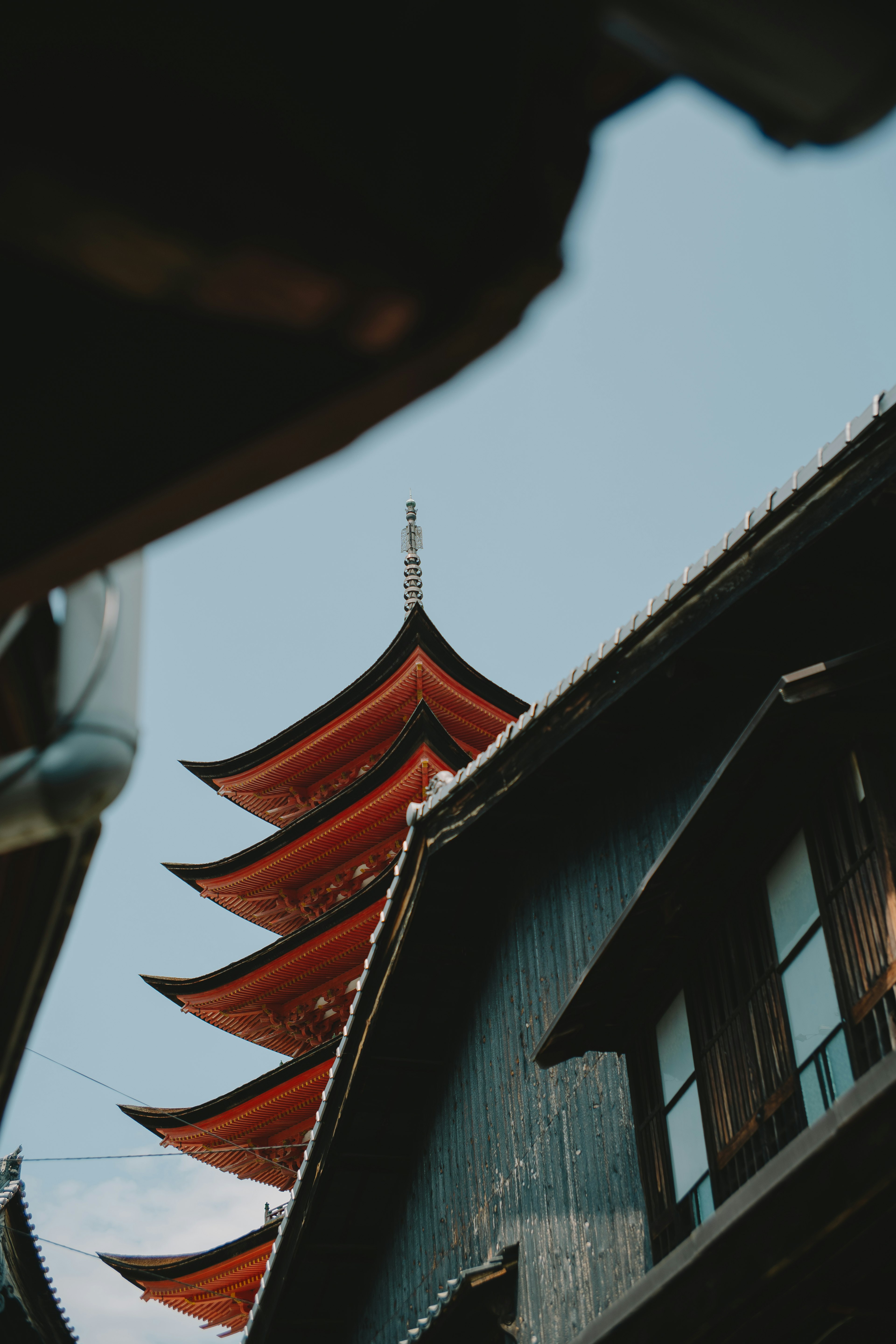 View of a five-story pagoda under a blue sky with traditional Japanese houses