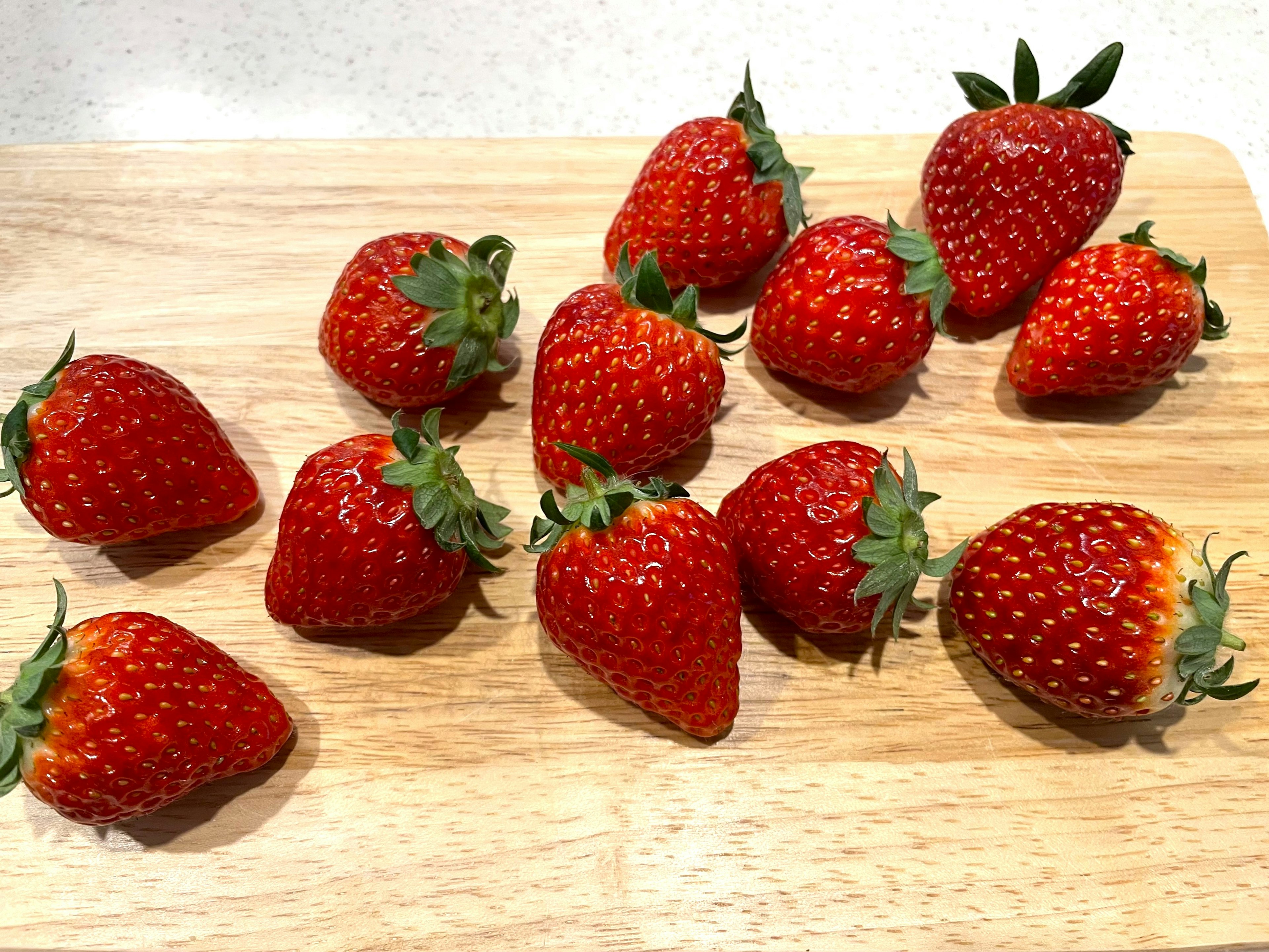 Frische Erdbeeren auf einem Holzbrett angeordnet mit etwa zwölf Stück