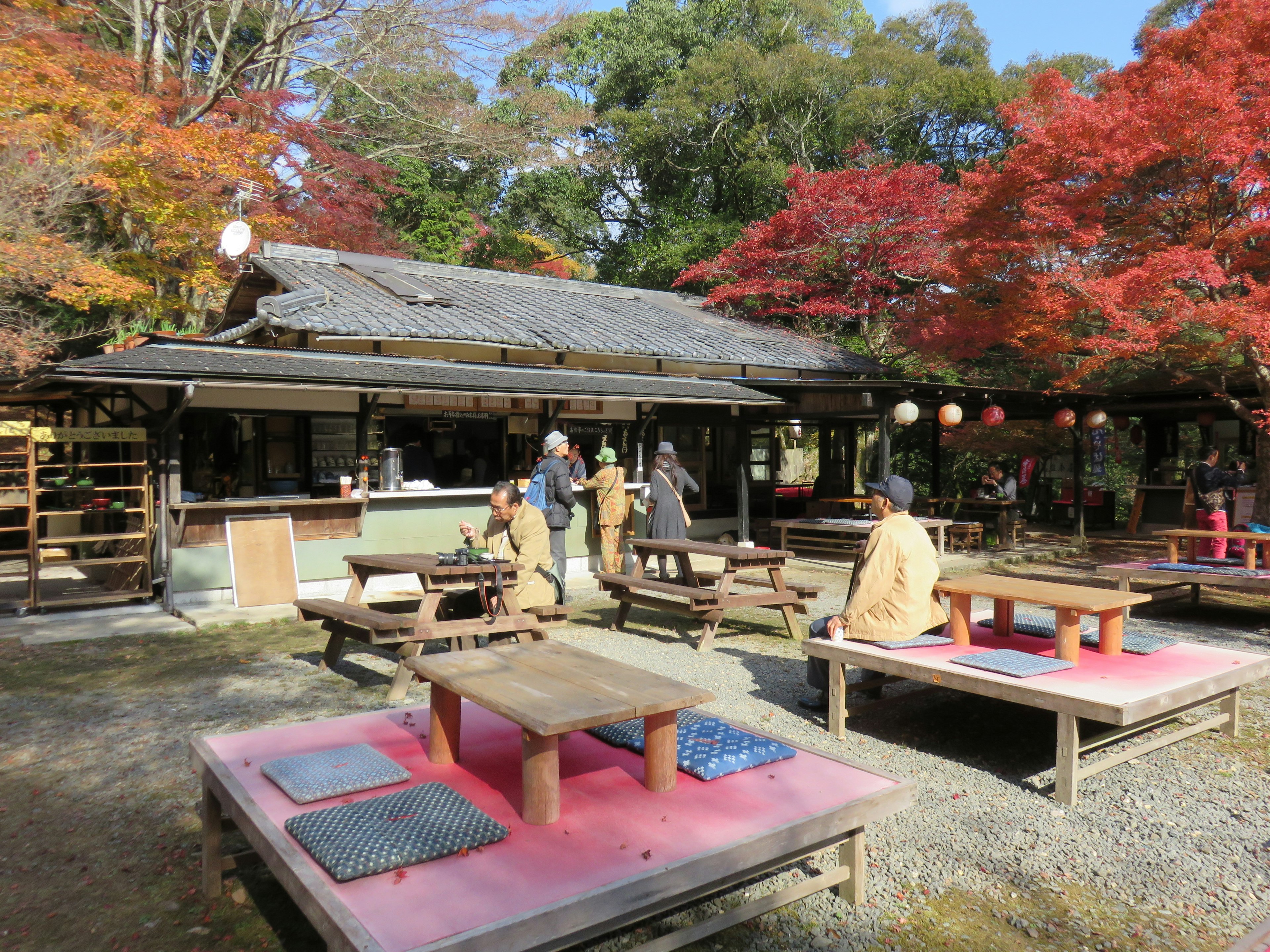 Casa de té japonesa tradicional rodeada de follaje de otoño y mesas de madera