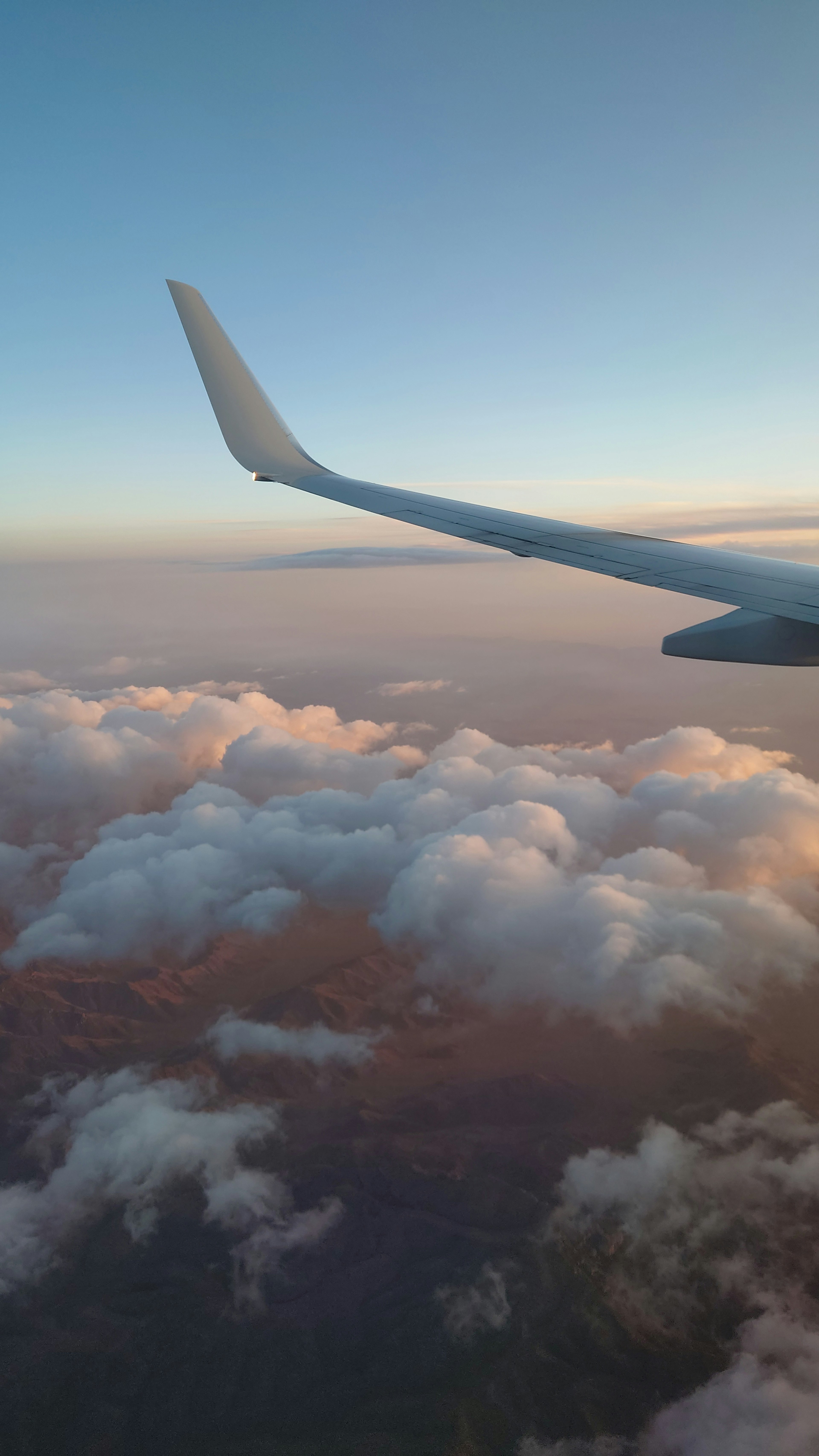 Sayap pesawat di atas awan saat matahari terbenam